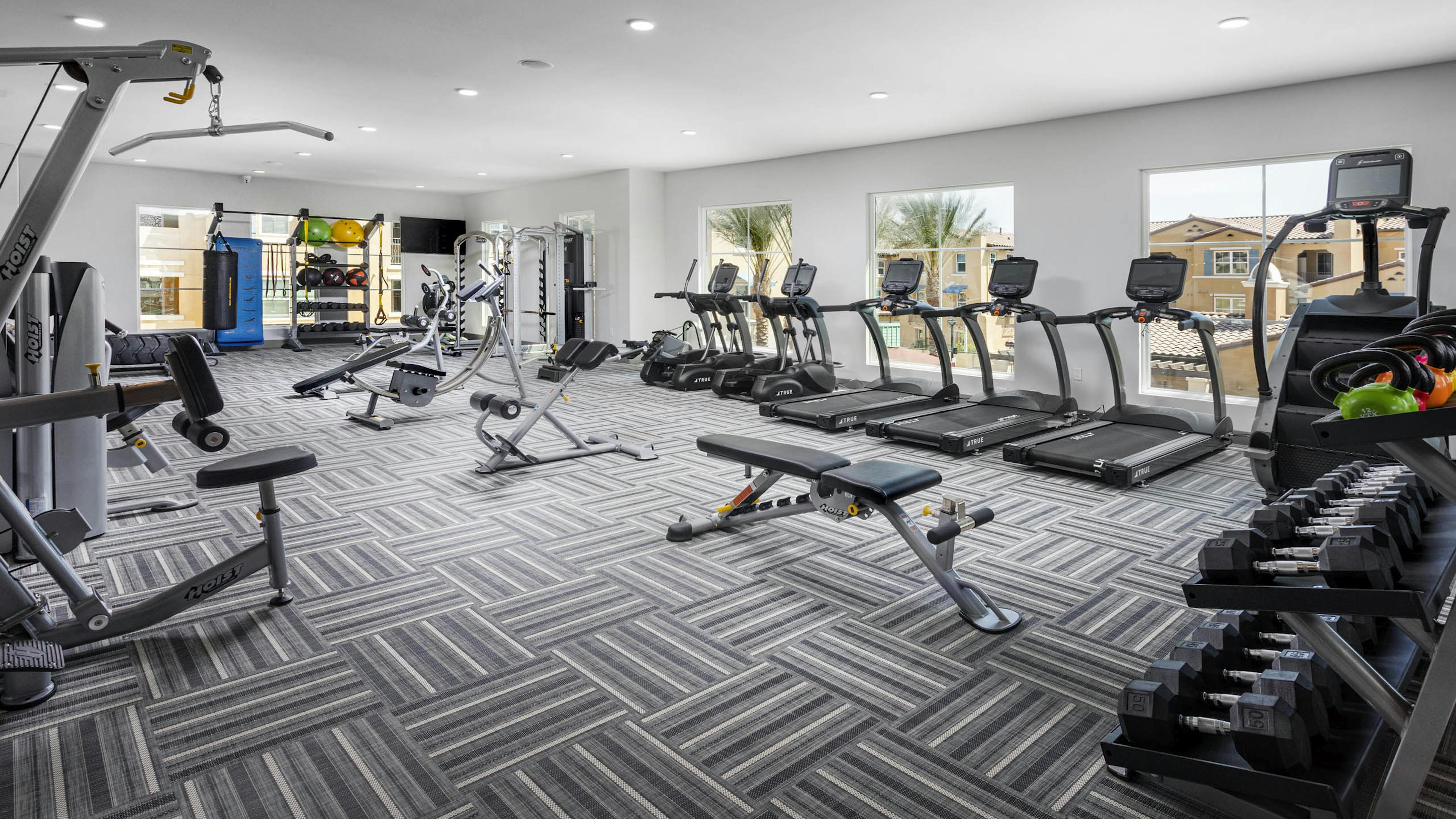 AMLI Camarillo fitness center with treadmills, strength equipment, punching bag and large windows overlooking the pool area