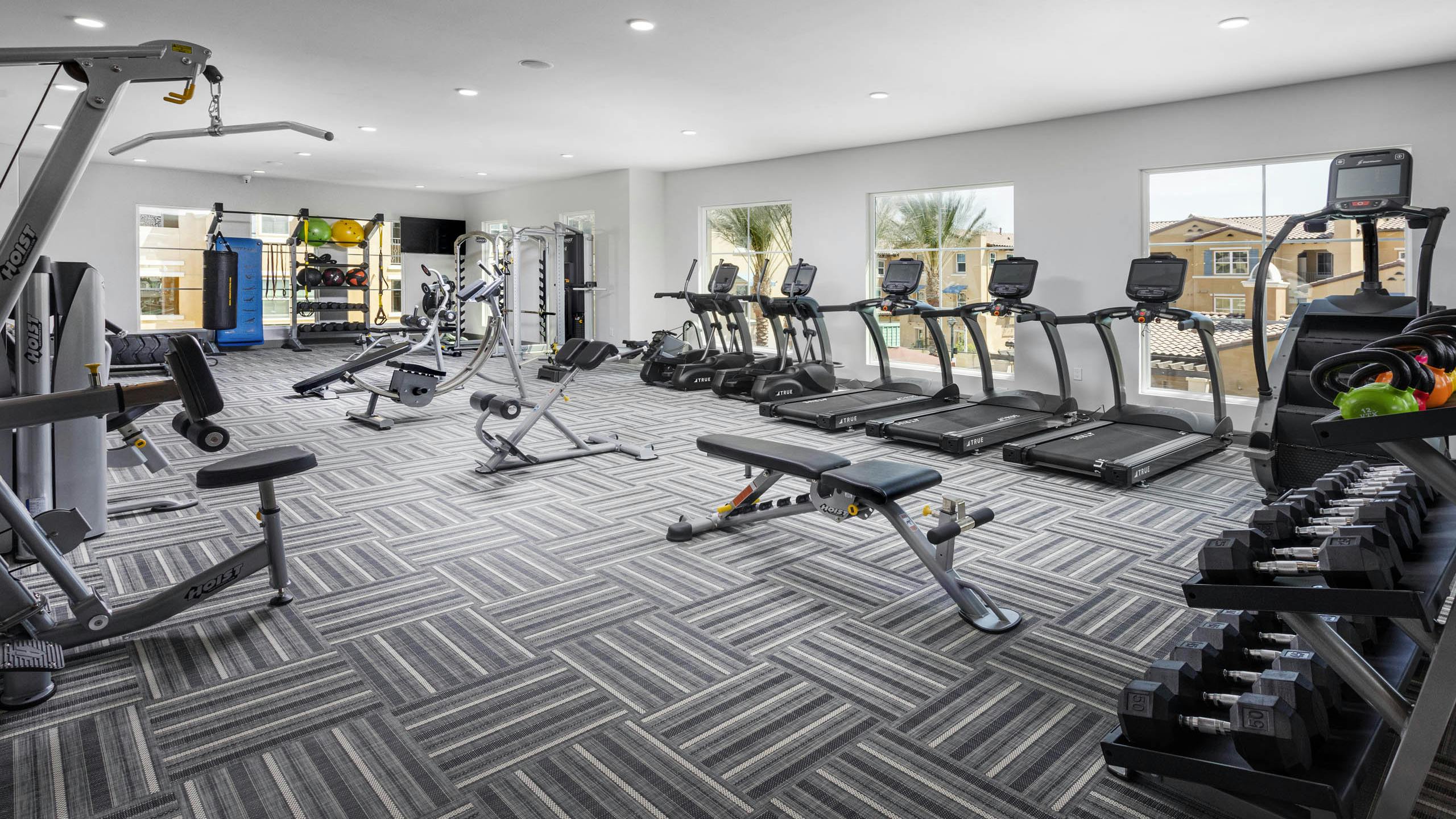AMLI Camarillo fitness center with treadmills, strength equipment, punching bag and large windows overlooking the pool area
