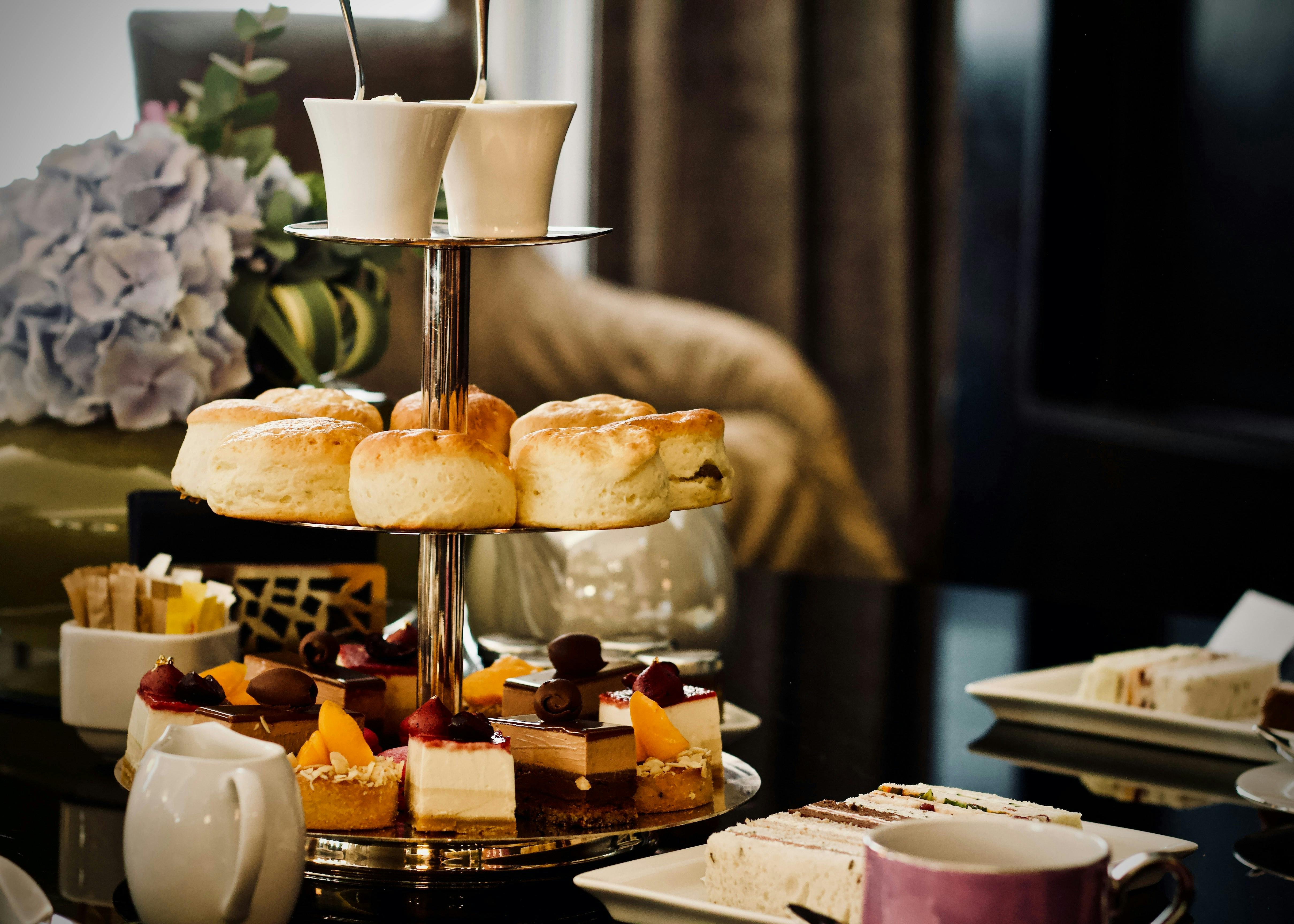 A three tiered tea tray with scones, pastries and desserts