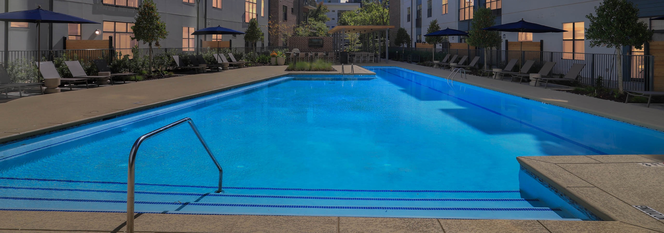 Dusk view of pool deck, lounge chairs and umbrellas at AMLI Old 4th Ward