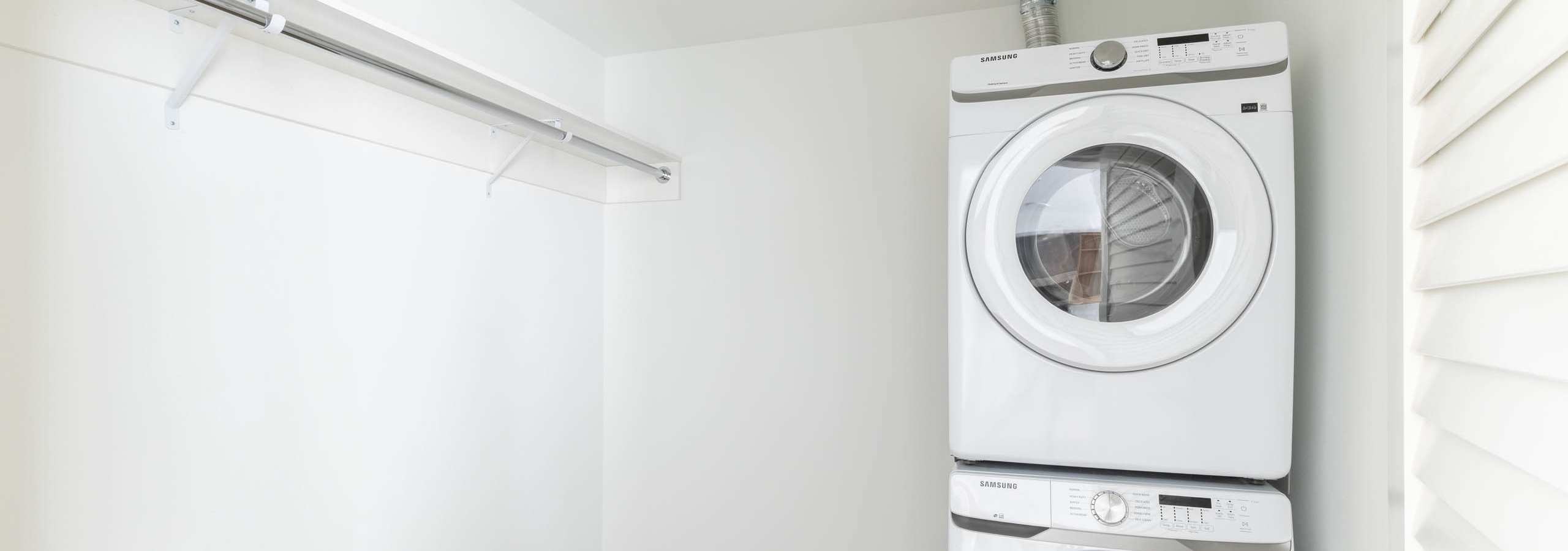 Interior view of laundry area with stacked washer dryer and adjacent walk-in closet space at AMLI Redmond Way apartments.