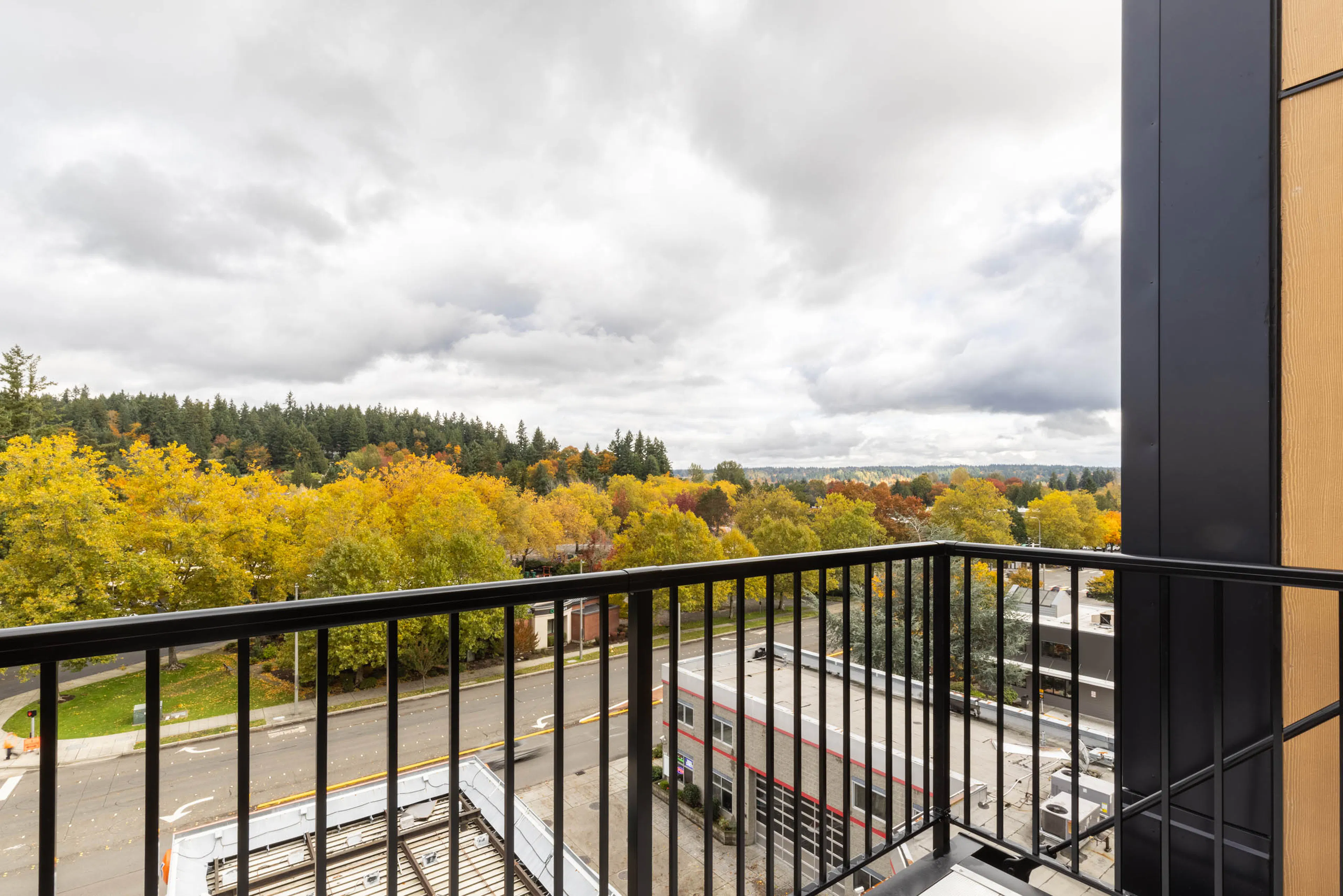 Balcony view from AMLI Redmond Way apartment with black railing, fall trees, and surrounding streets and rooftops below.