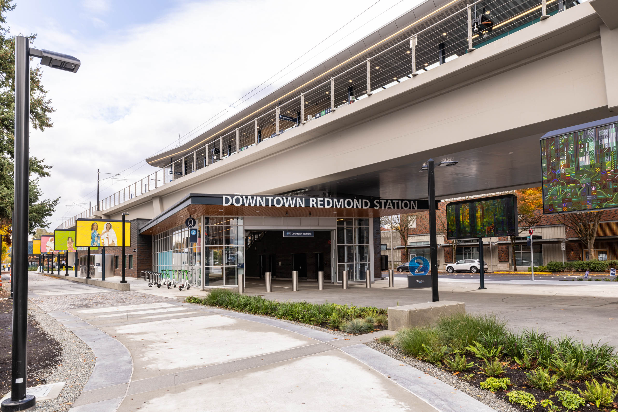 Street-level view of Downtown Redmond Station near AMLI Redmond Way apartments with bike racks, signage, and walkway.