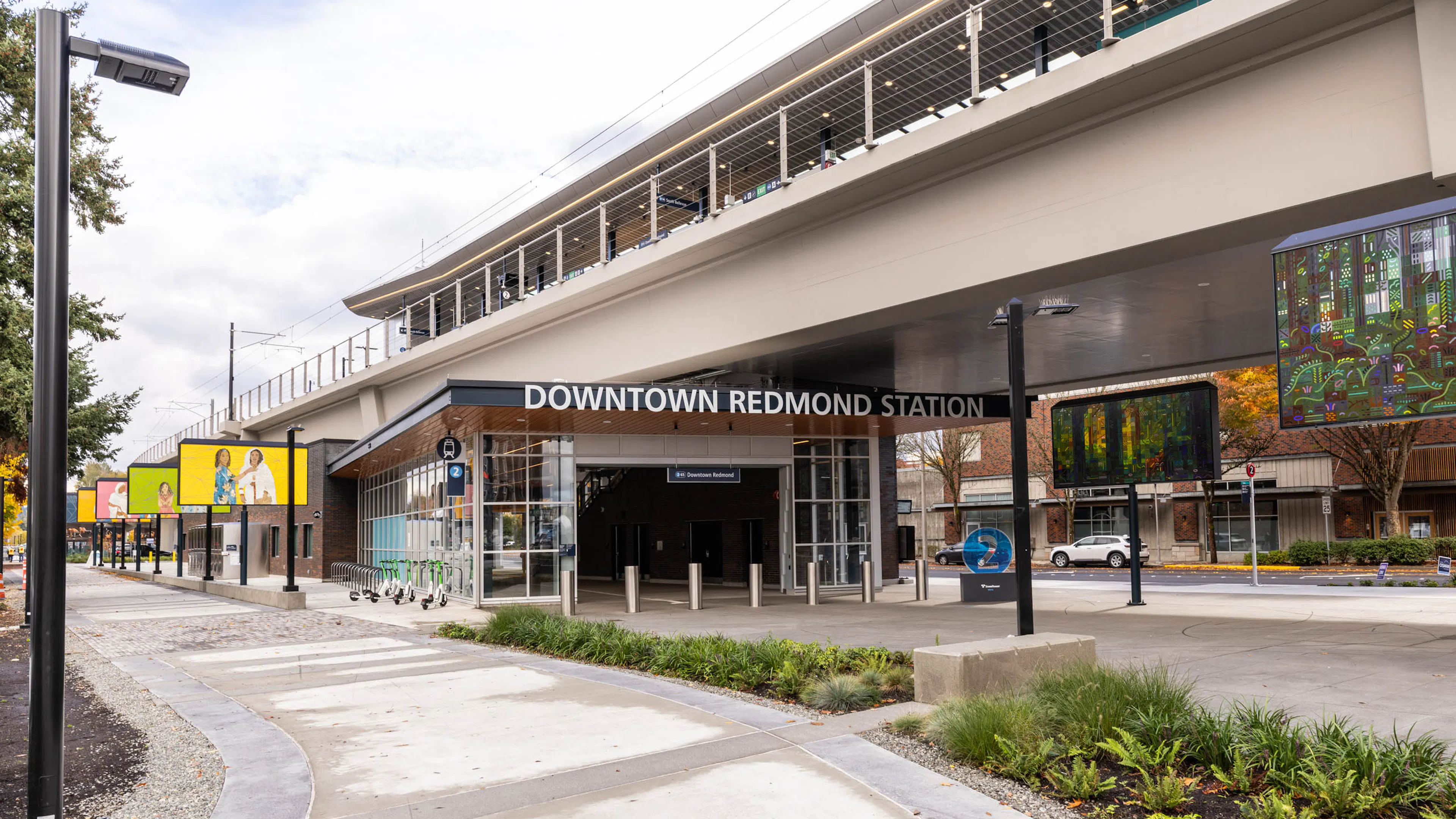 Street-level view of Downtown Redmond Station near AMLI Redmond Way apartments with bike racks, signage, and walkway.