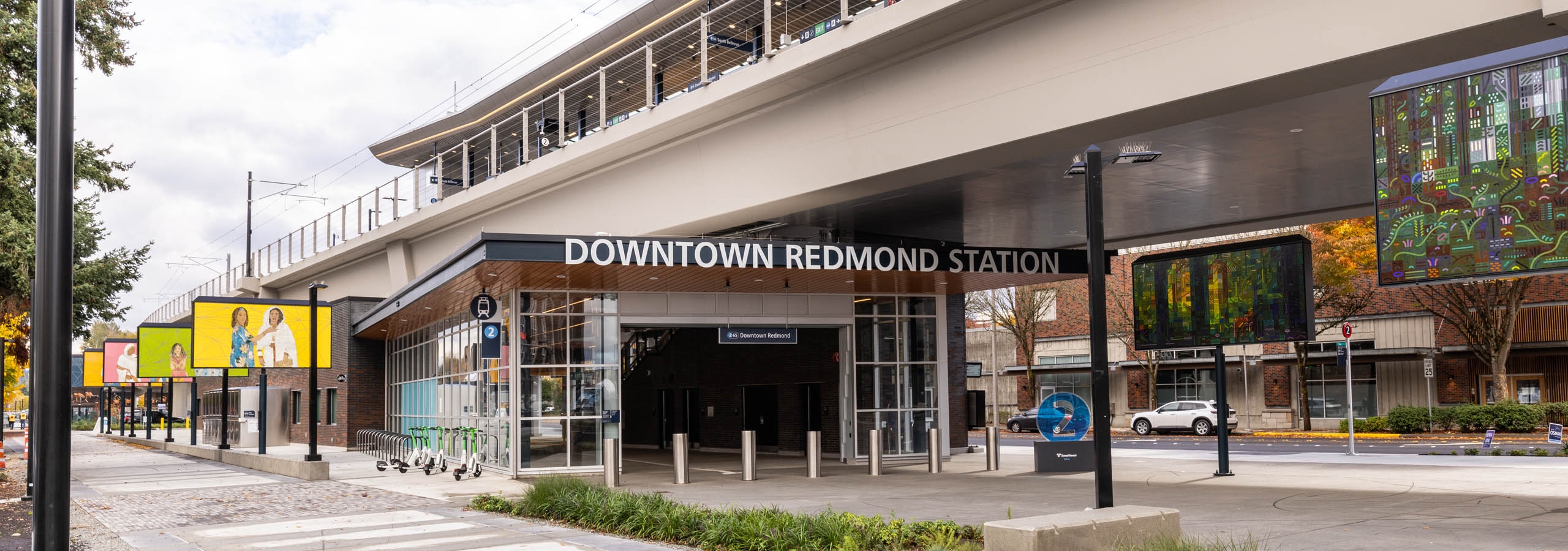 Street-level view of Downtown Redmond Station near AMLI Redmond Way apartments with bike racks, signage, and walkway.