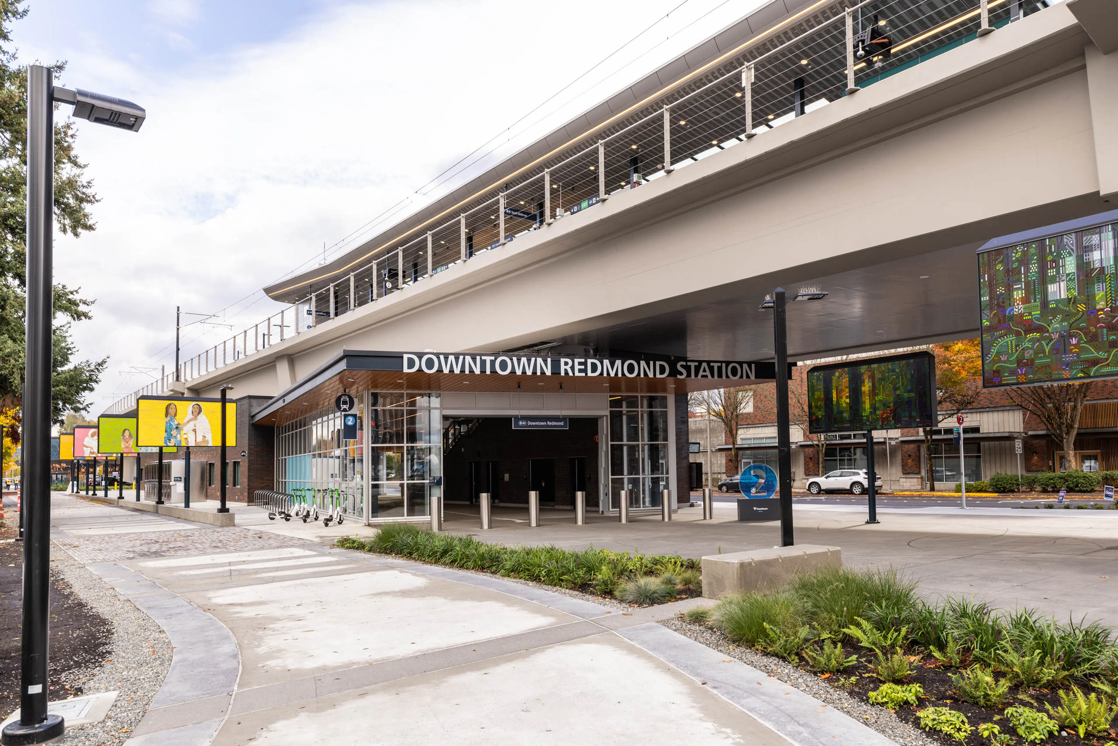Street-level view of Downtown Redmond Station near AMLI Redmond Way apartments with bike racks, signage, and walkway.