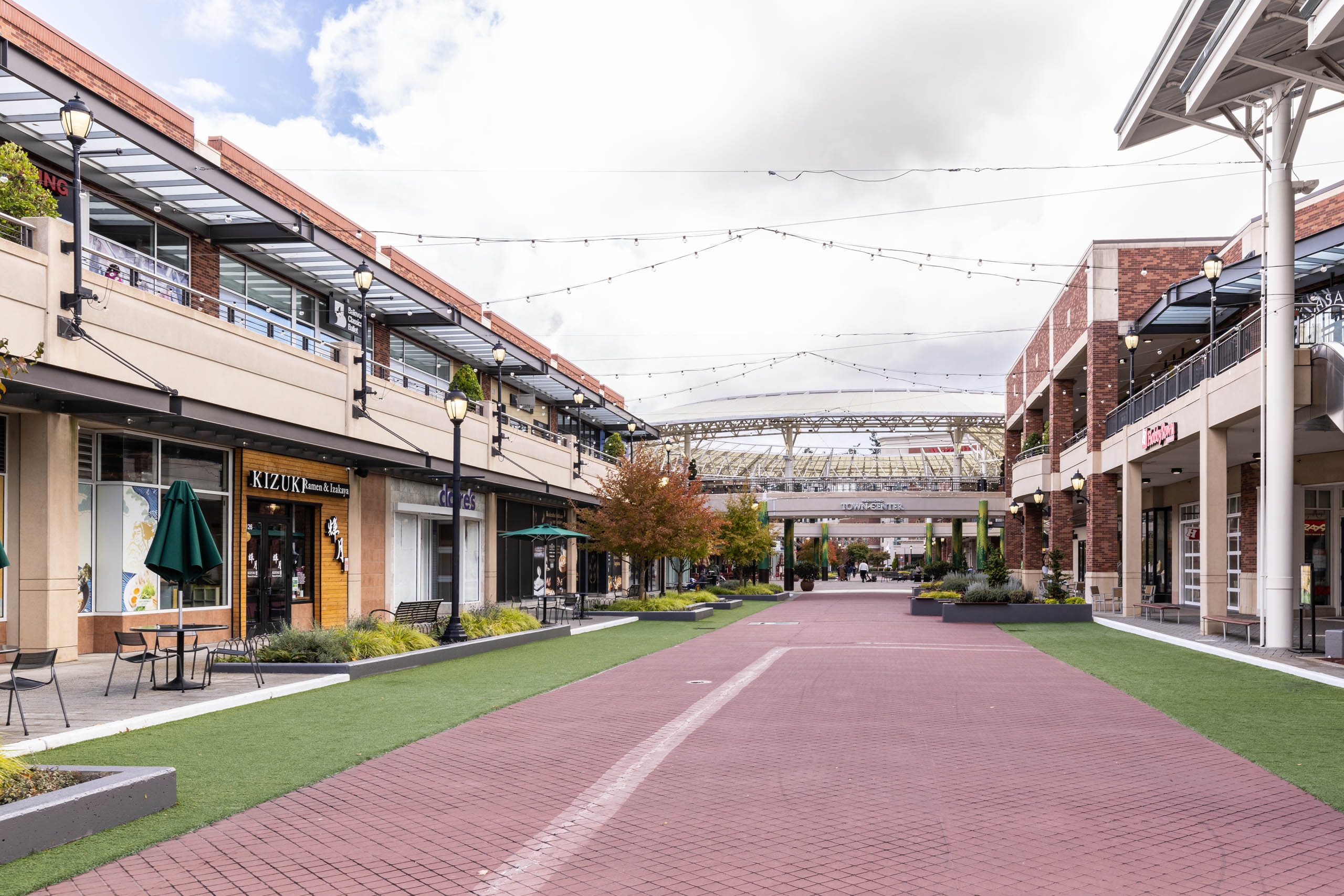 Daytime view of Redmond Town Center near AMLI Redmond Way apartments with outdoor shops, dining, and hanging string lights.