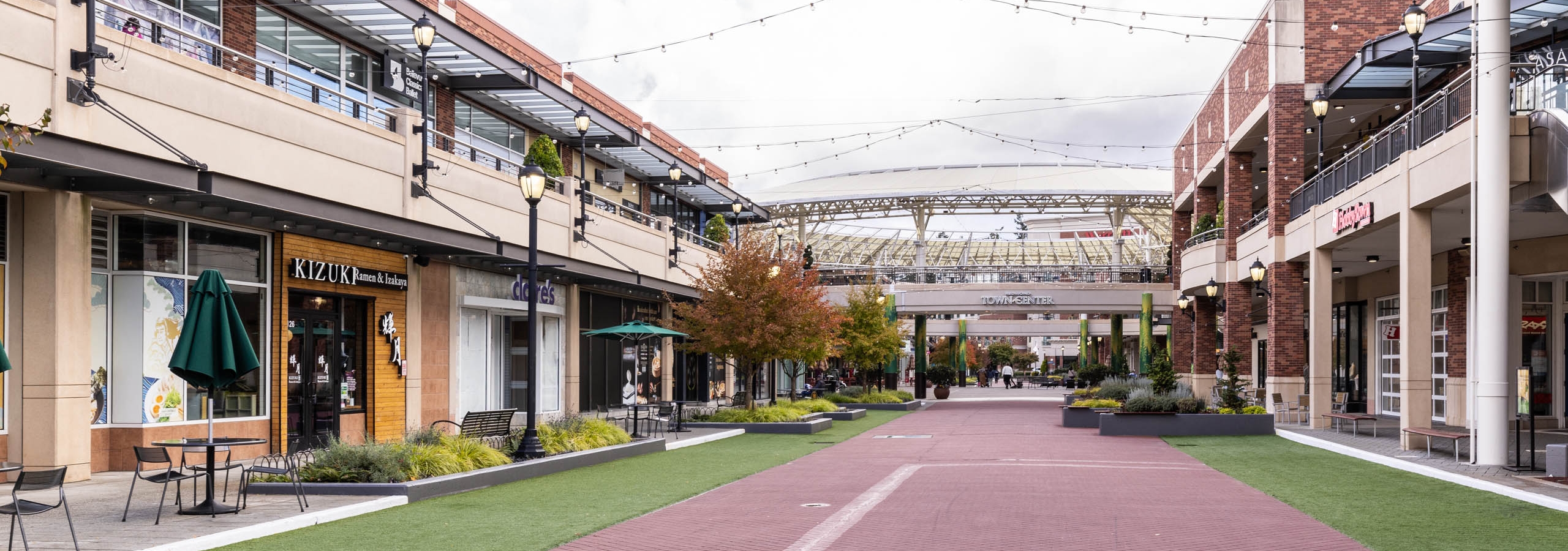 Daytime view of Redmond Town Center near AMLI Redmond Way apartments with outdoor shops, dining, and hanging string lights.