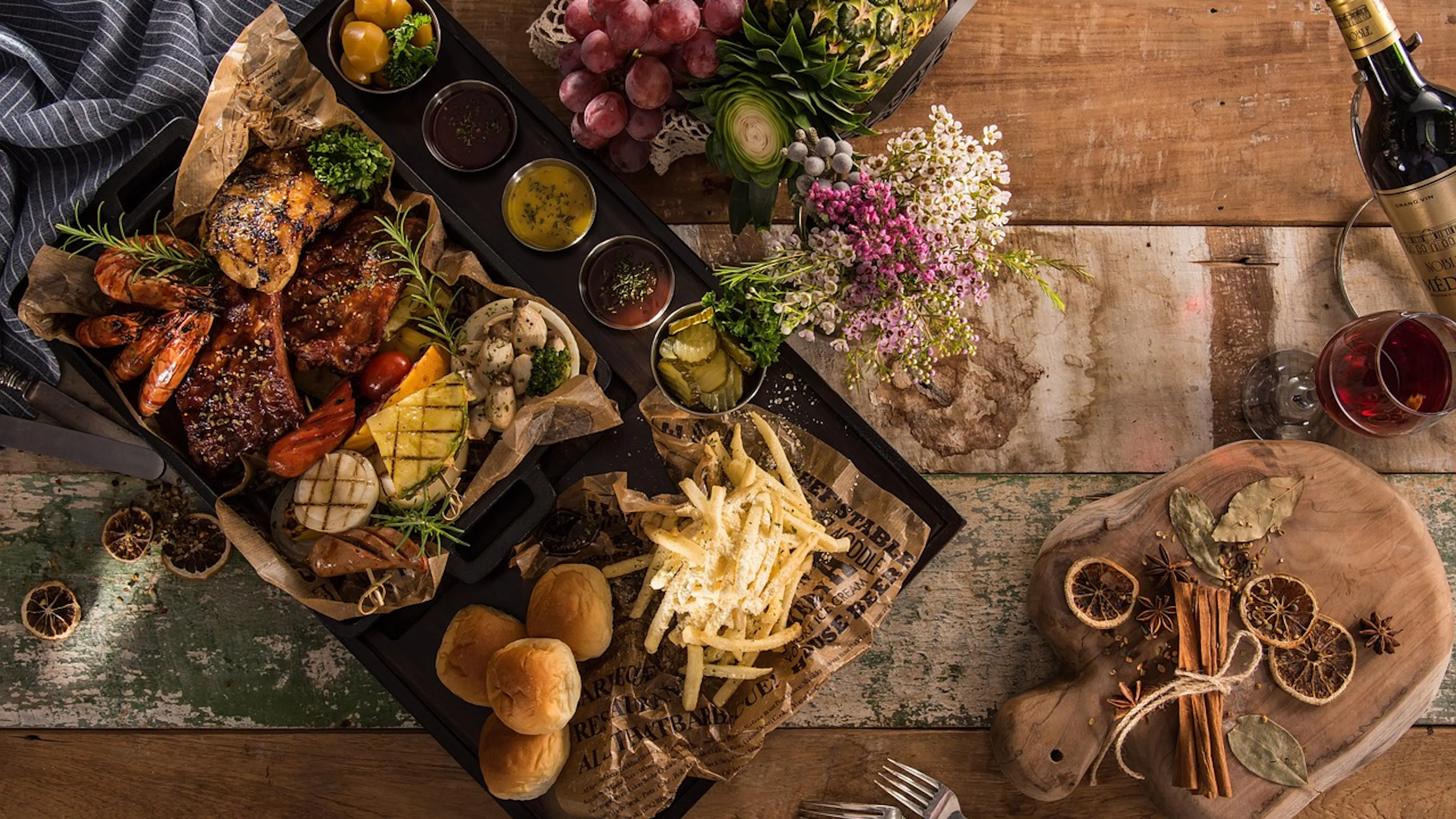 tray with chicken, steak, veggies, wine on wooden boards