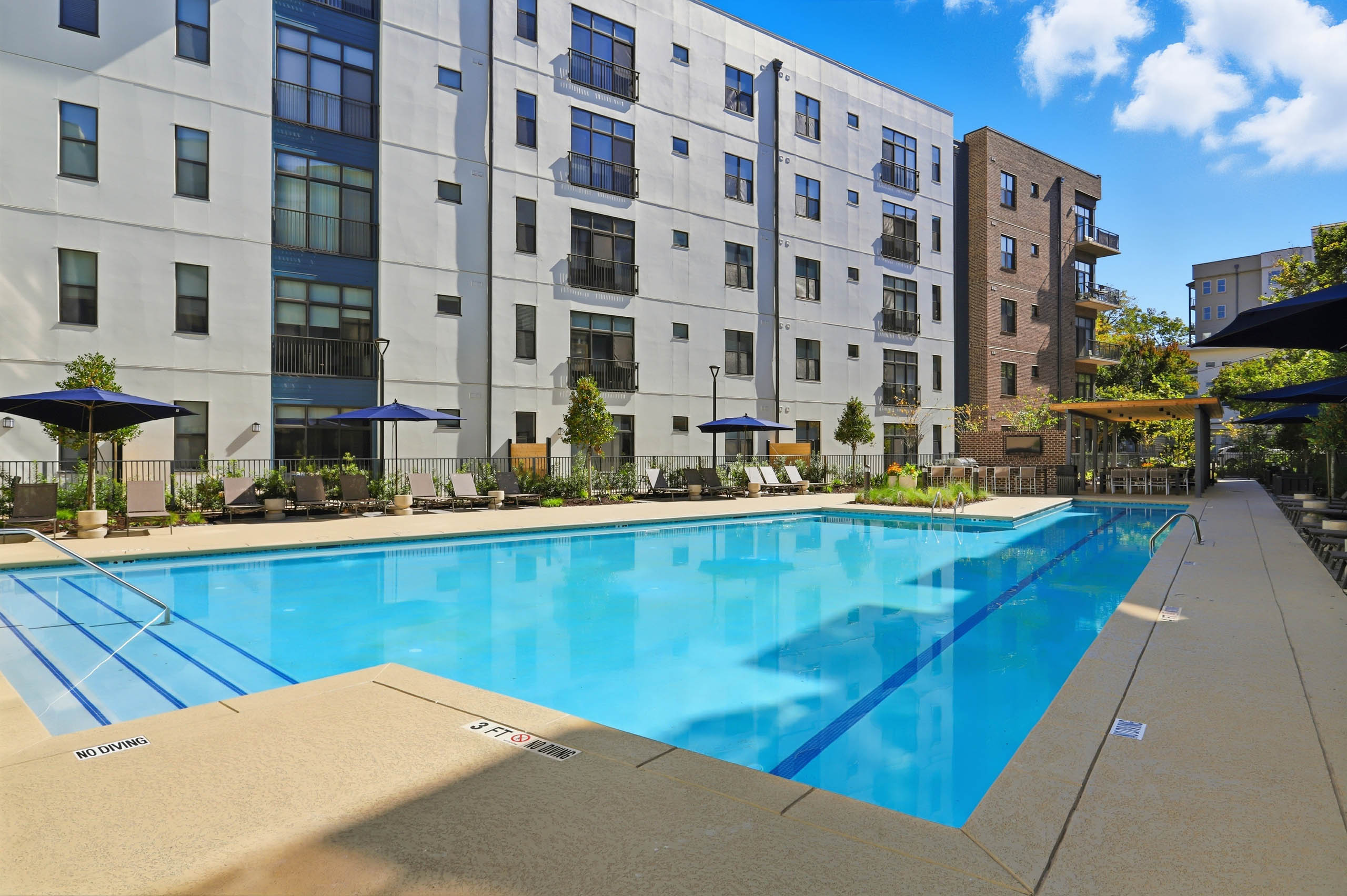 Corner view of pool deck at AMLI Old 4th Ward with lounge chairs and umbrellas