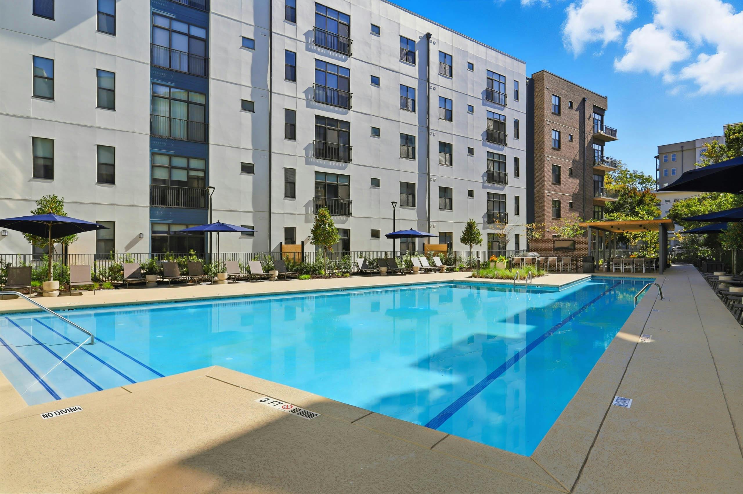 Corner view of pool deck at AMLI Old 4th Ward with lounge chairs and umbrellas