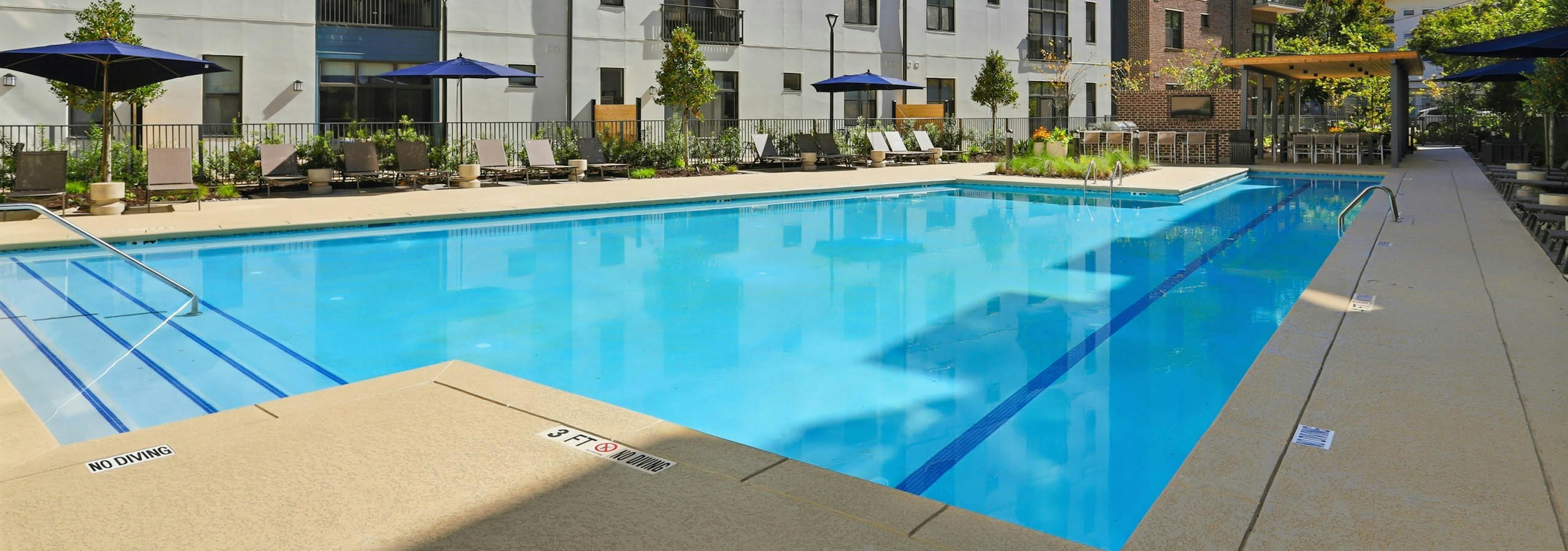 Corner view of pool deck at AMLI Old 4th Ward with lounge chairs and umbrellas