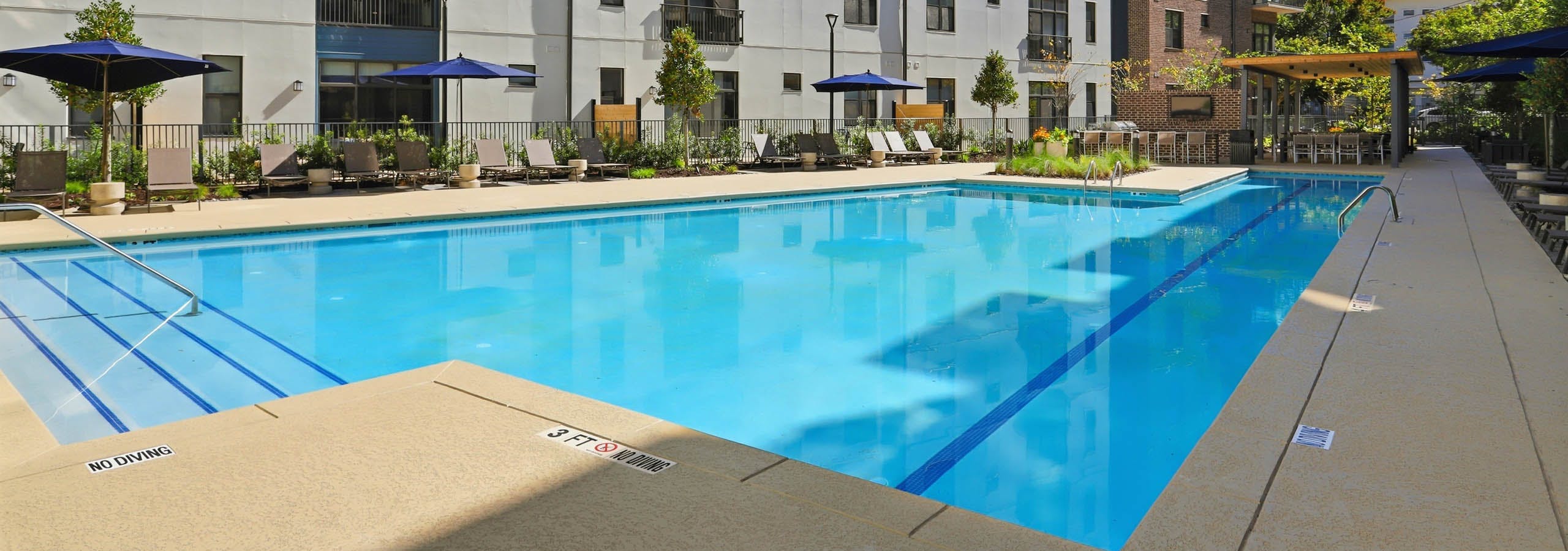 Corner view of pool deck at AMLI Old 4th Ward with lounge chairs and umbrellas
