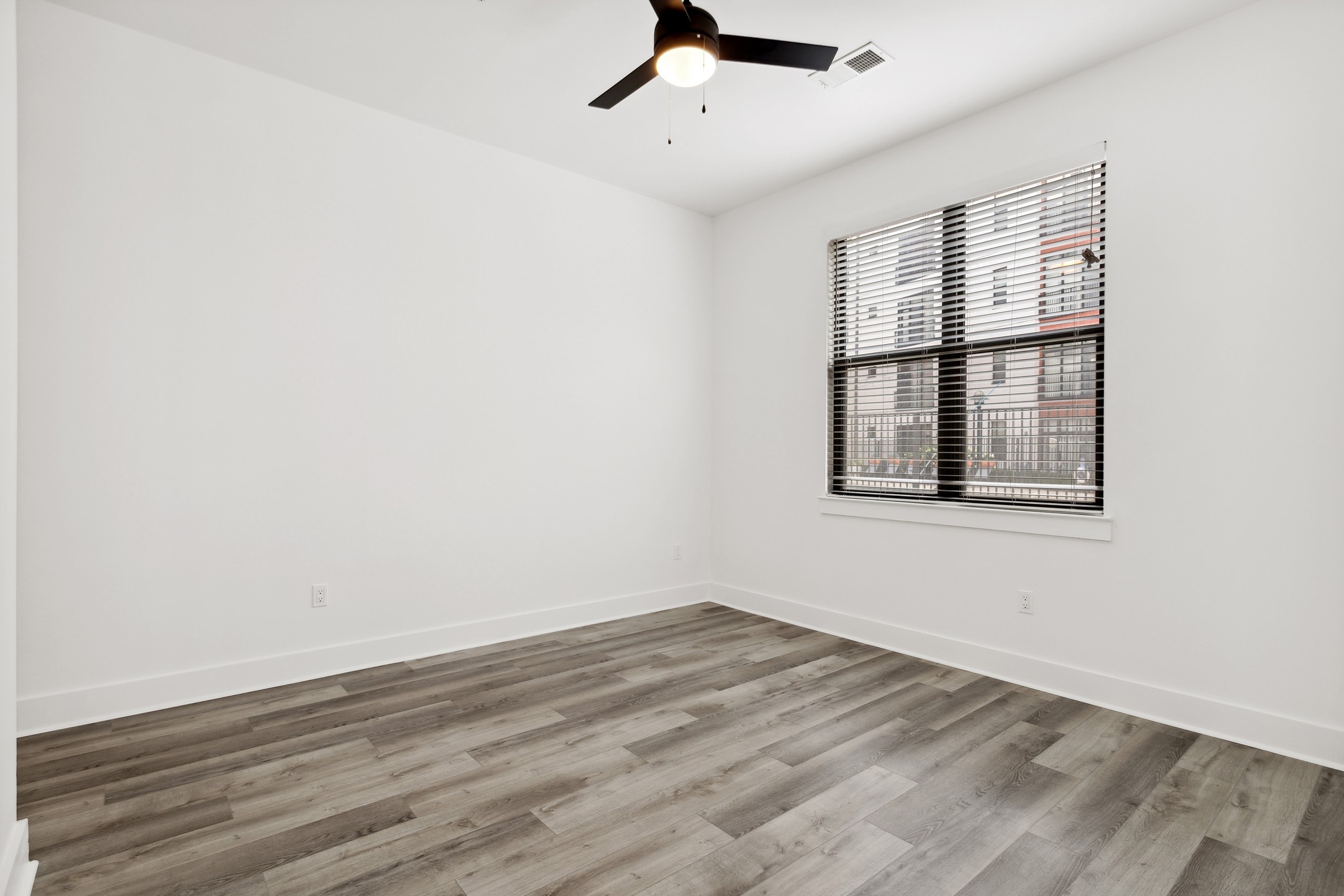 Interior view of bedroom with gray flooring and white walls and a black framed window with a black ceiling fan at AMLI Old 4th Ward