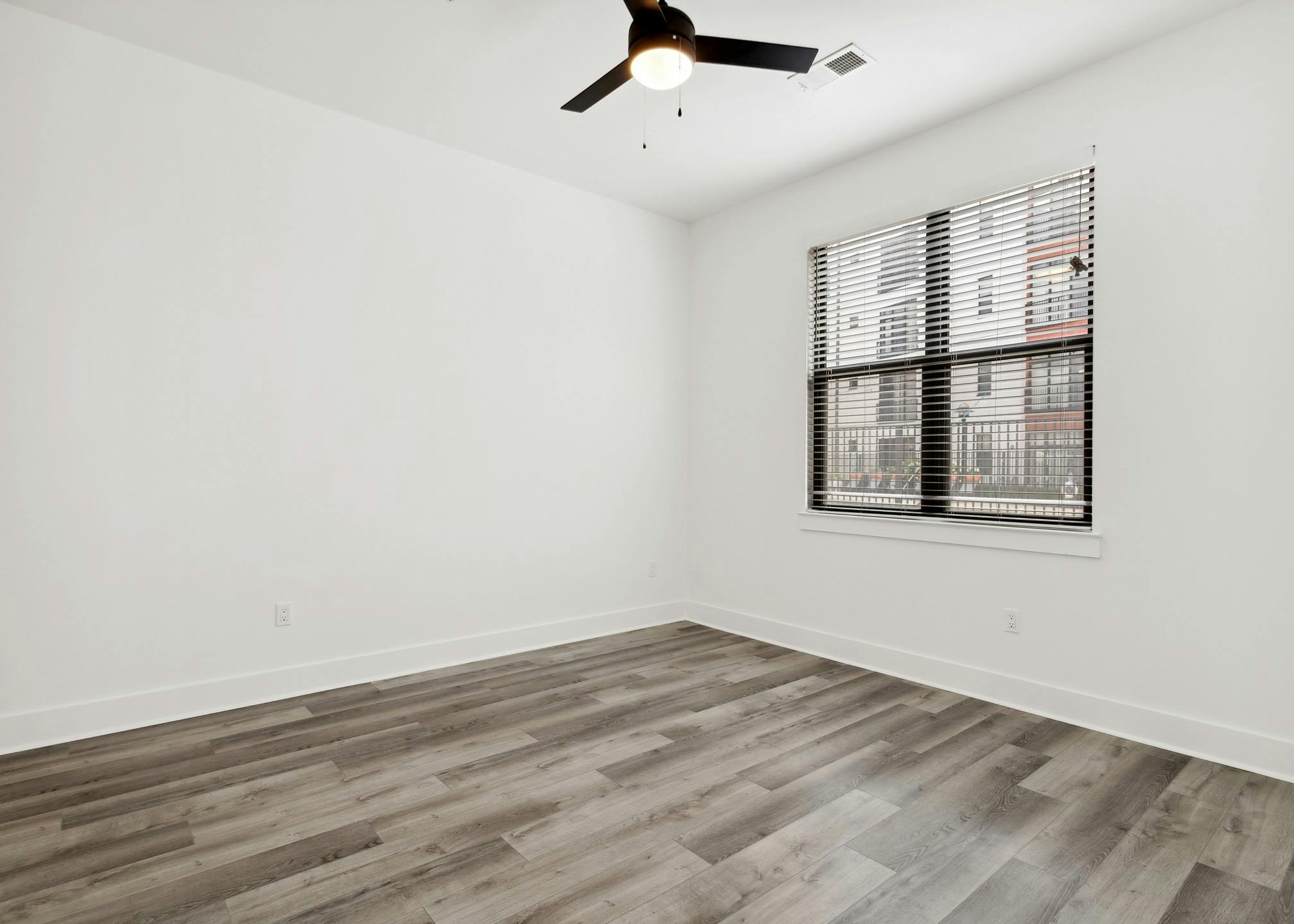 Interior view of bedroom with gray flooring and white walls and a black framed window with a black ceiling fan at AMLI Old 4th Ward