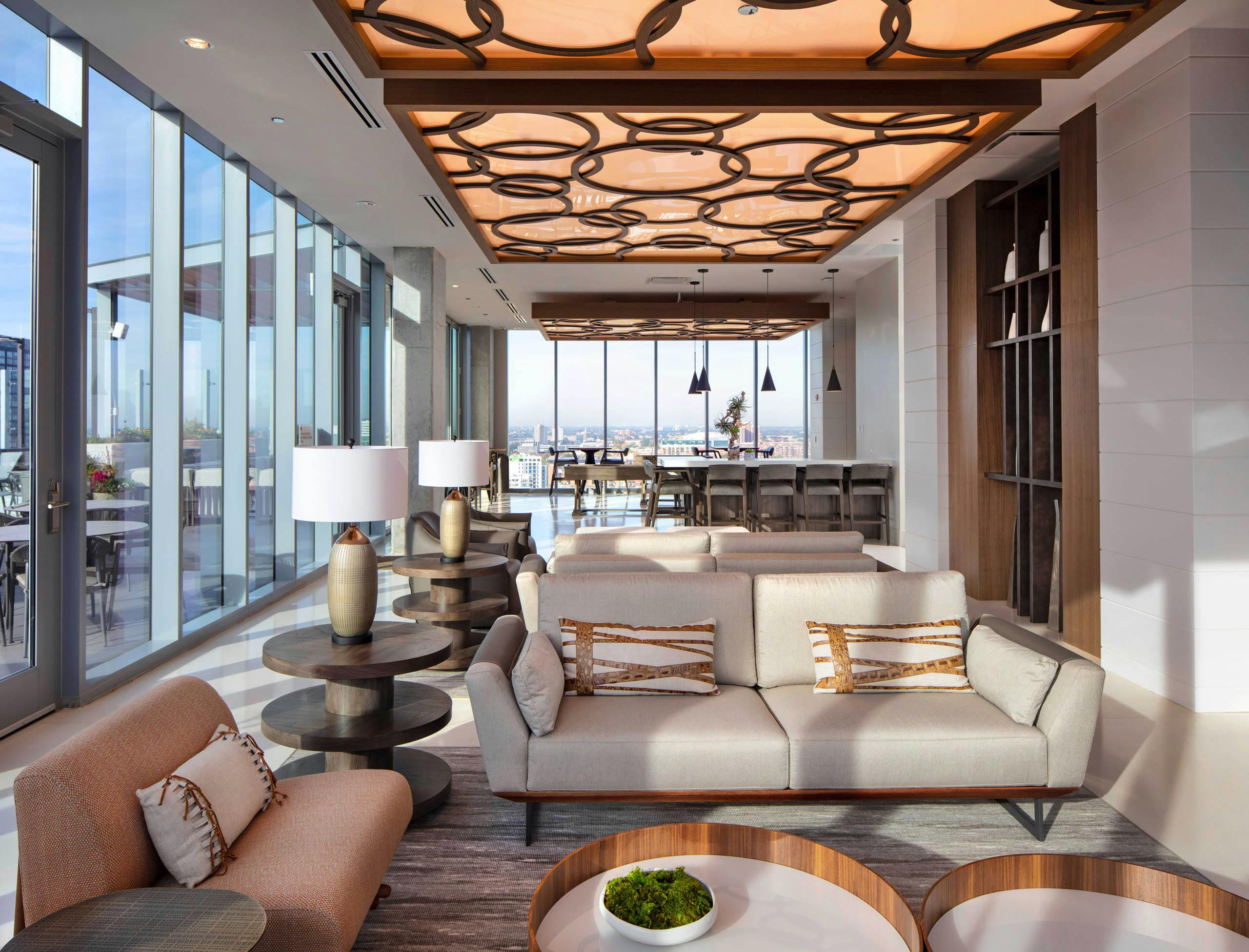 AMLI West Loop Resident Lounge featuring a sofa, armchairs, bar seating, and floor-to-ceiling windows with a city view.