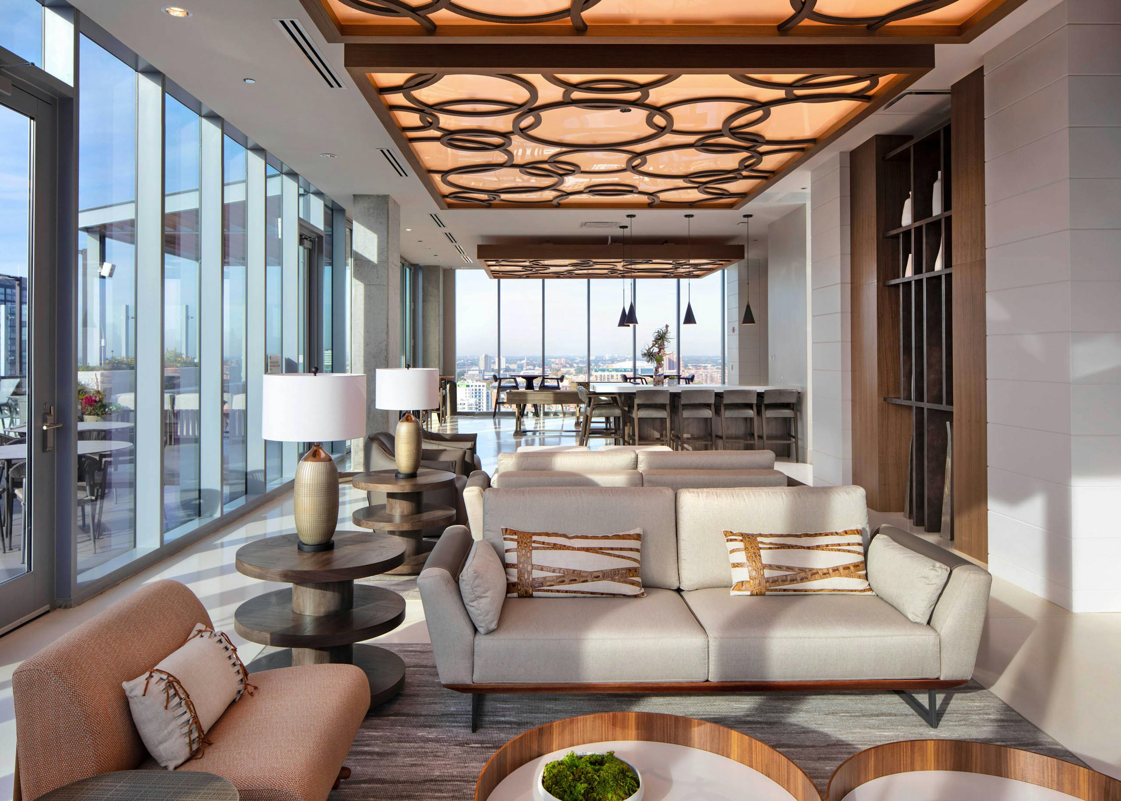 AMLI West Loop Resident Lounge featuring a sofa, armchairs, bar seating, and floor-to-ceiling windows with a city view.