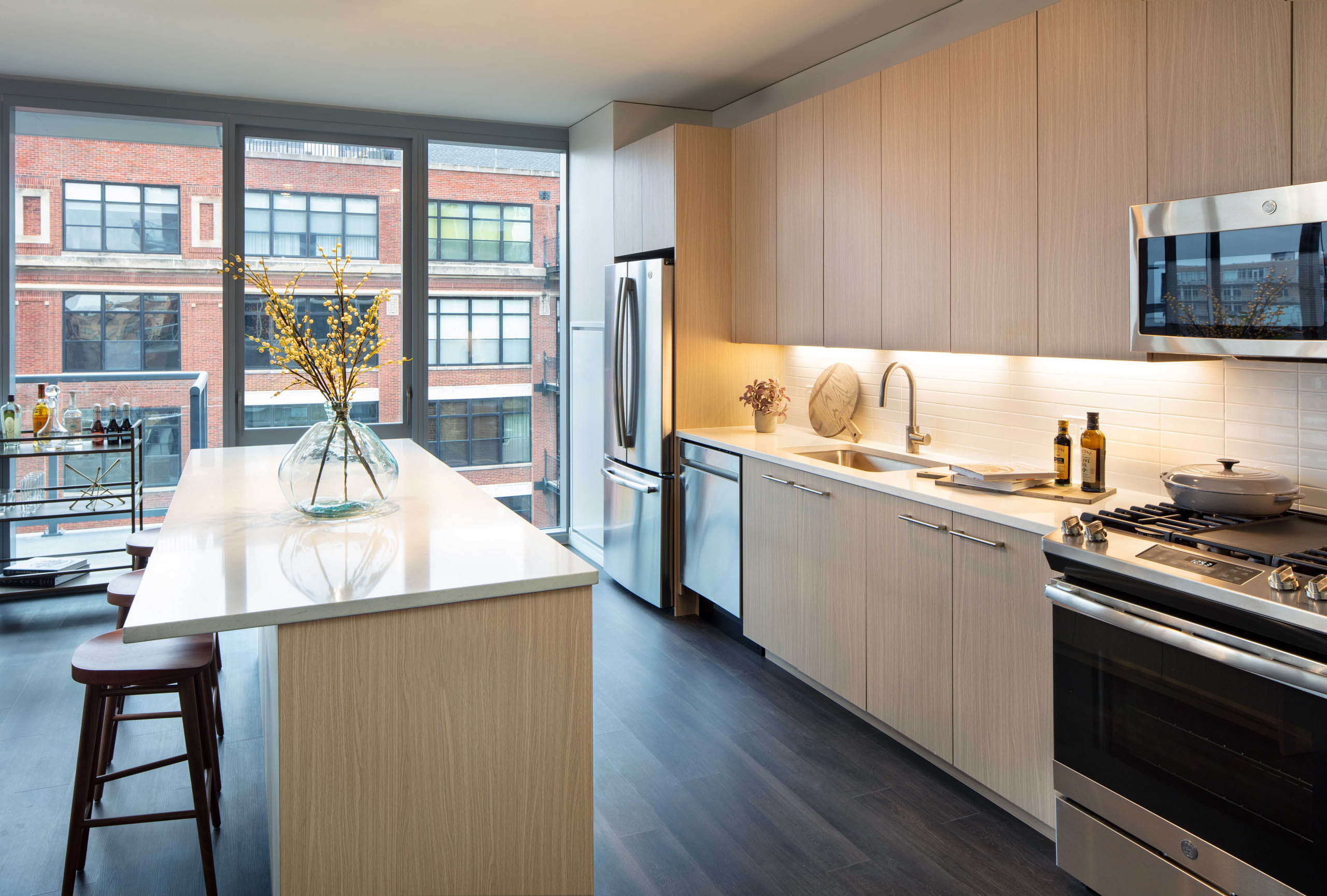 AMLI West Loop modern apartment kitchen and island lined by floor to ceiling windows showing daytime view