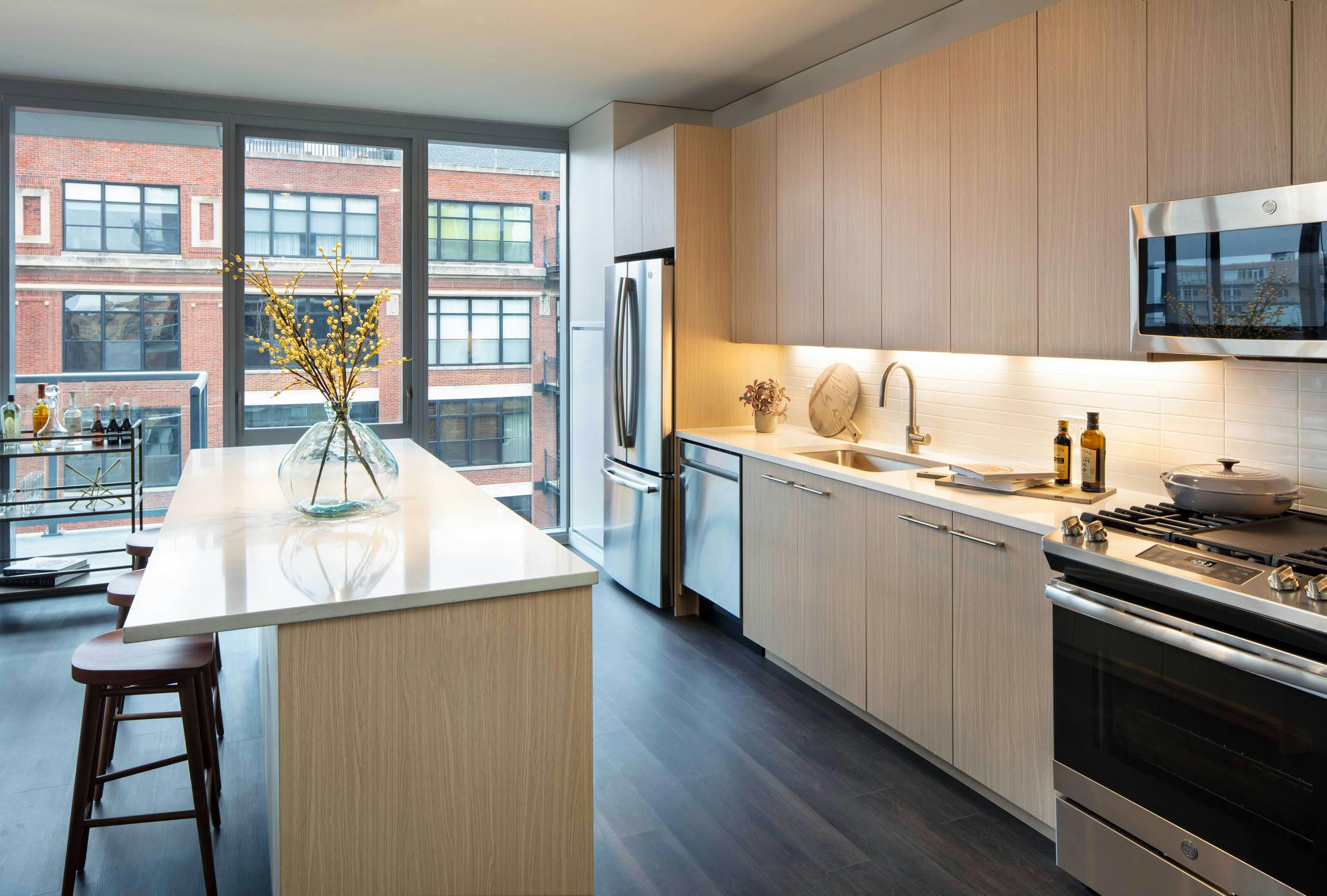 AMLI West Loop modern apartment kitchen and island lined by floor to ceiling windows showing daytime view