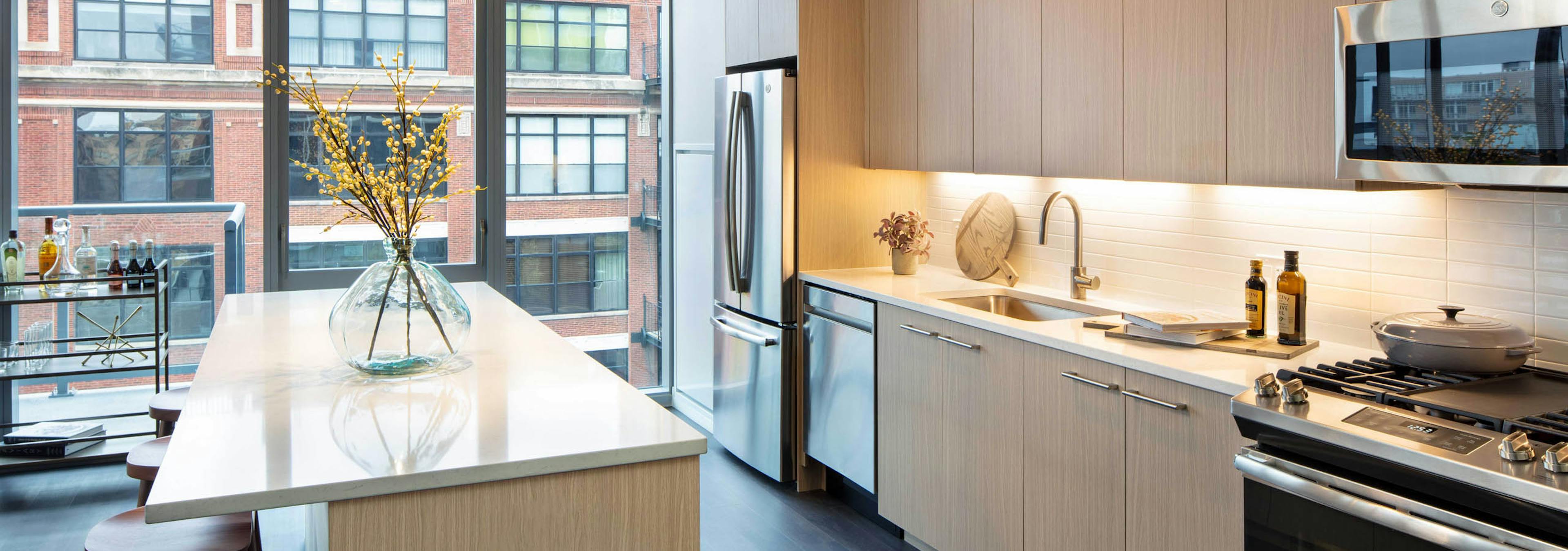 AMLI West Loop modern apartment kitchen and island lined by floor to ceiling windows showing daytime view