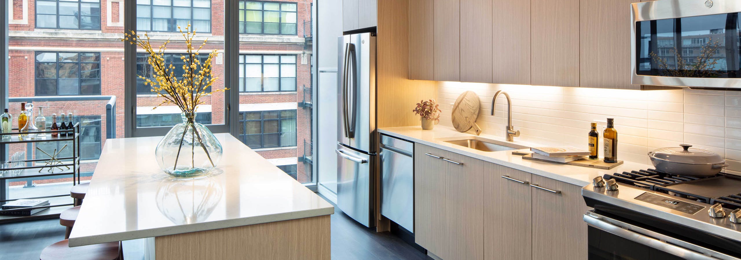 AMLI West Loop modern apartment kitchen and island lined by floor to ceiling windows showing daytime view