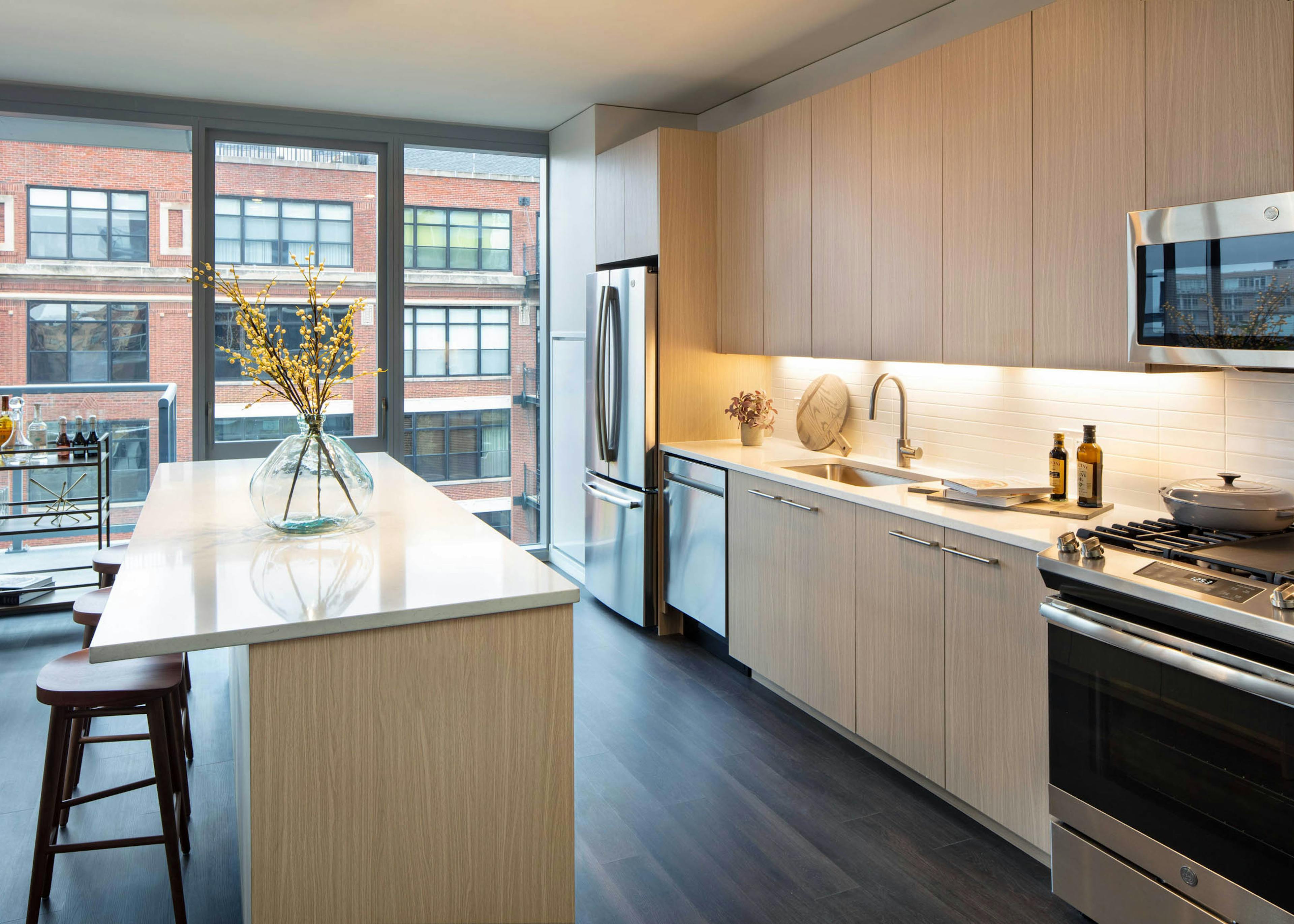 AMLI West Loop modern apartment kitchen and island lined by floor to ceiling windows showing daytime view