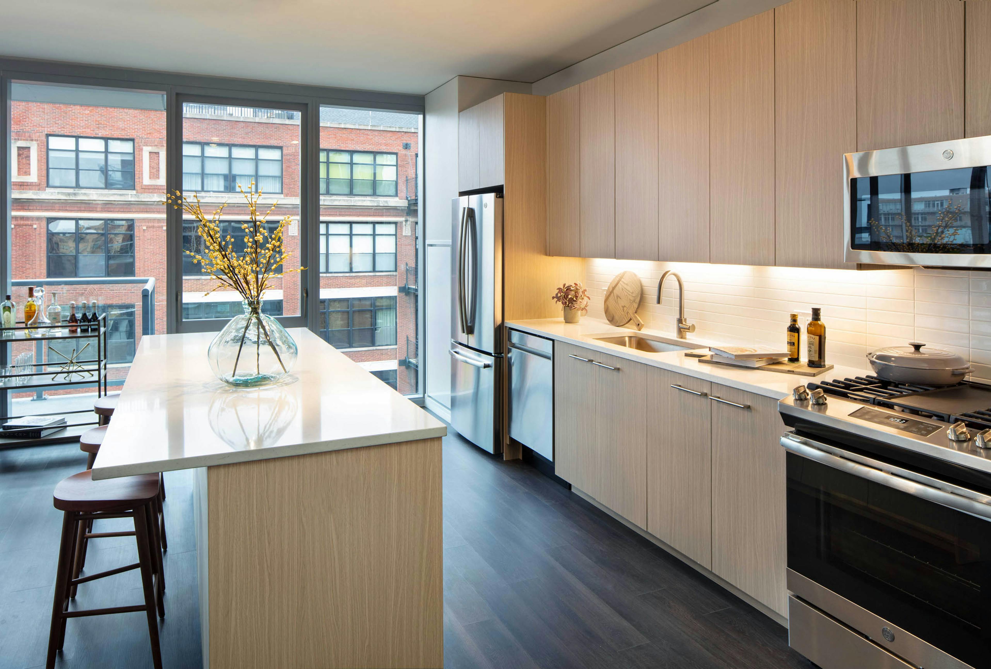AMLI West Loop modern apartment kitchen and island lined by floor to ceiling windows showing daytime view