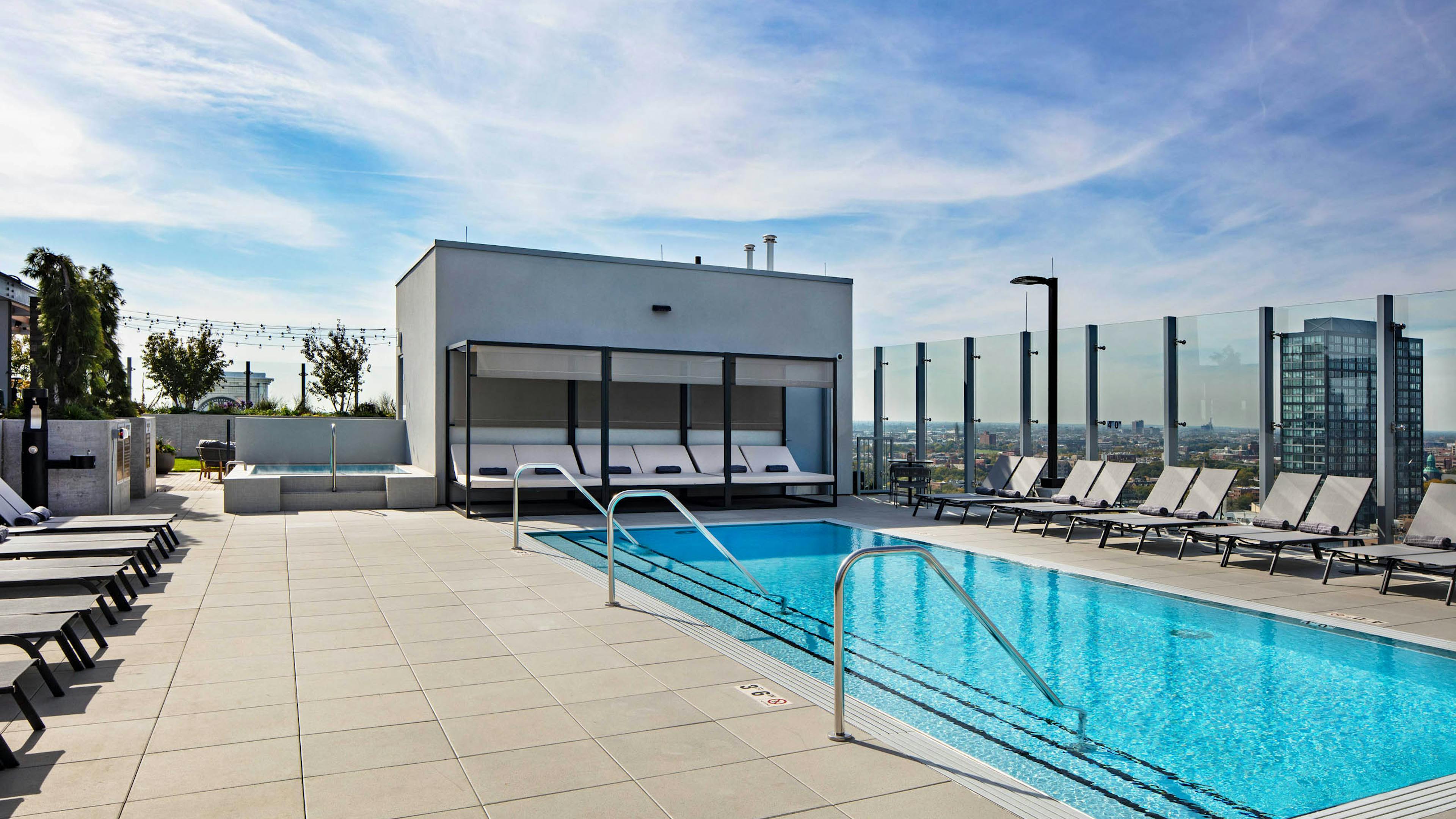Luxurious rooftop pool and spa at AMLI West Loop apartment building with grey lounge chairs and cabana.