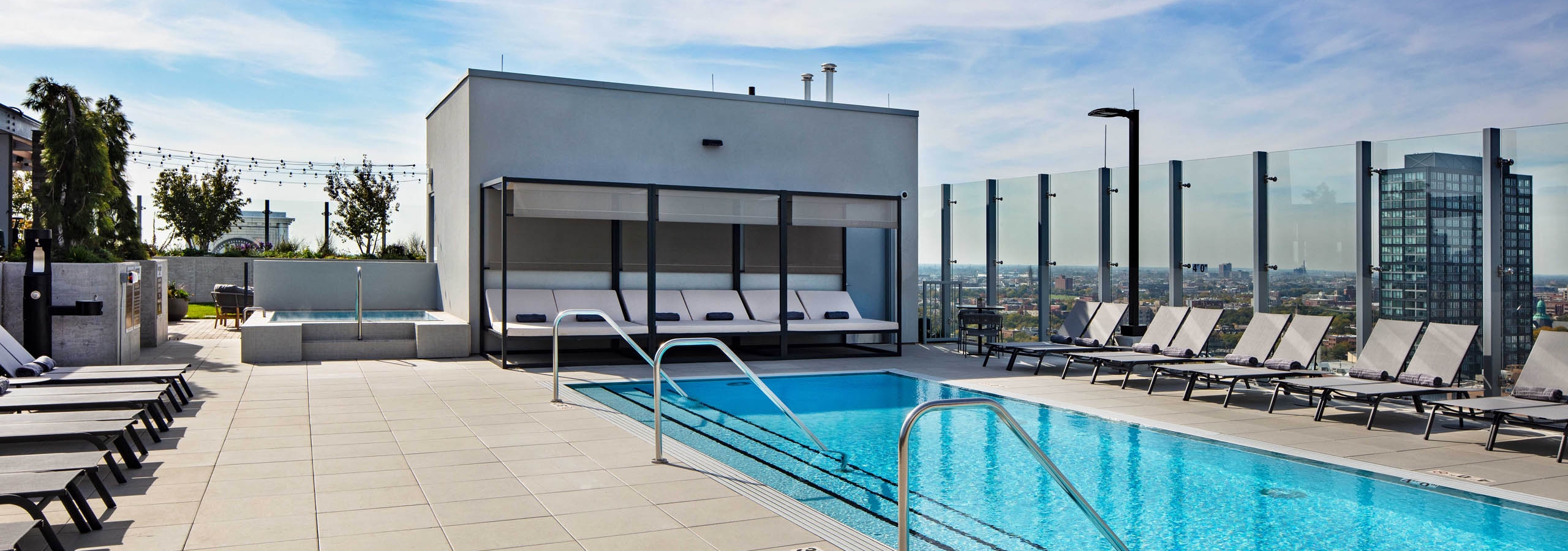 Luxurious rooftop pool and spa at AMLI West Loop apartment building with grey lounge chairs and cabana.