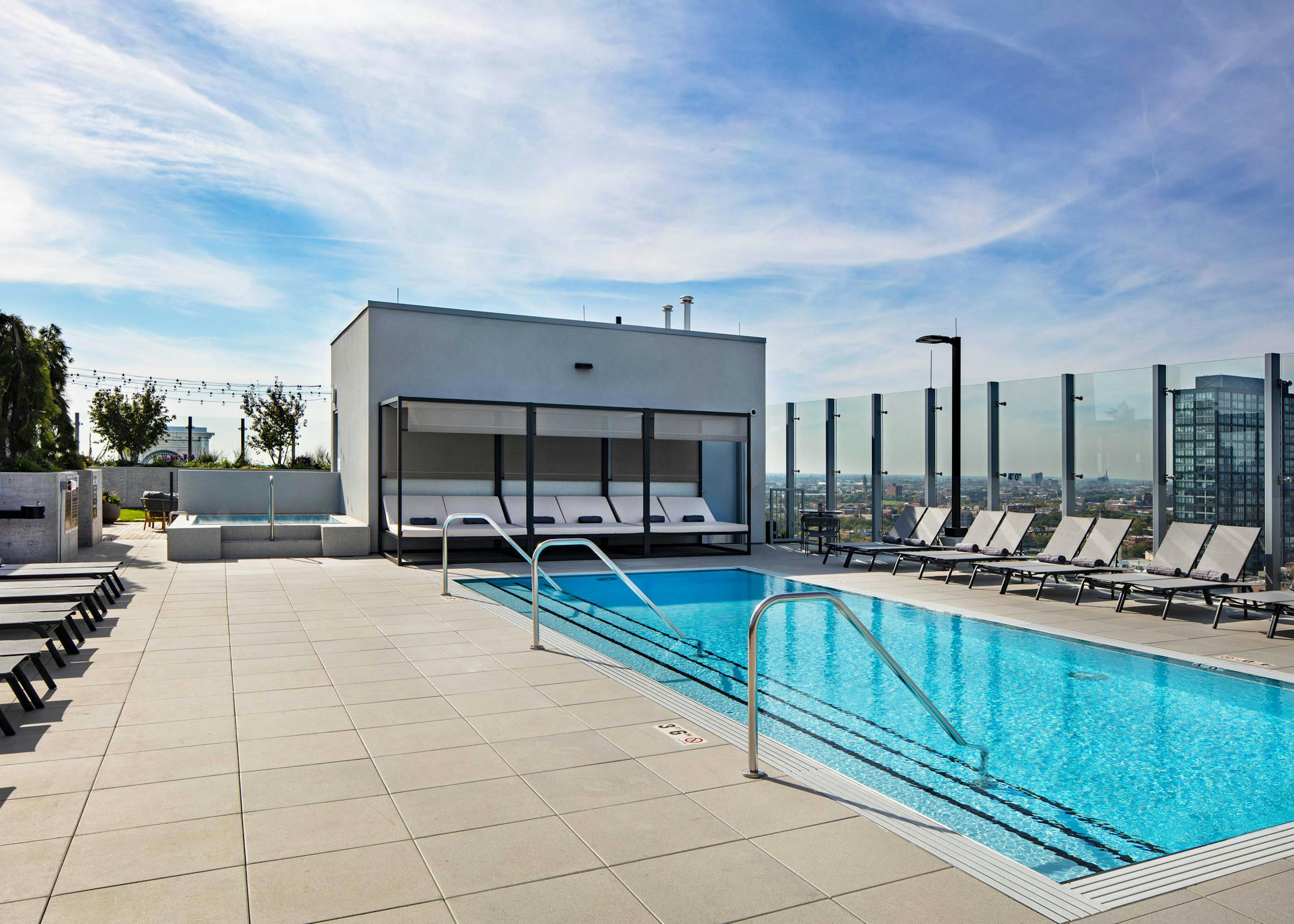 Luxurious rooftop pool and spa at AMLI West Loop apartment building with grey lounge chairs and cabana.