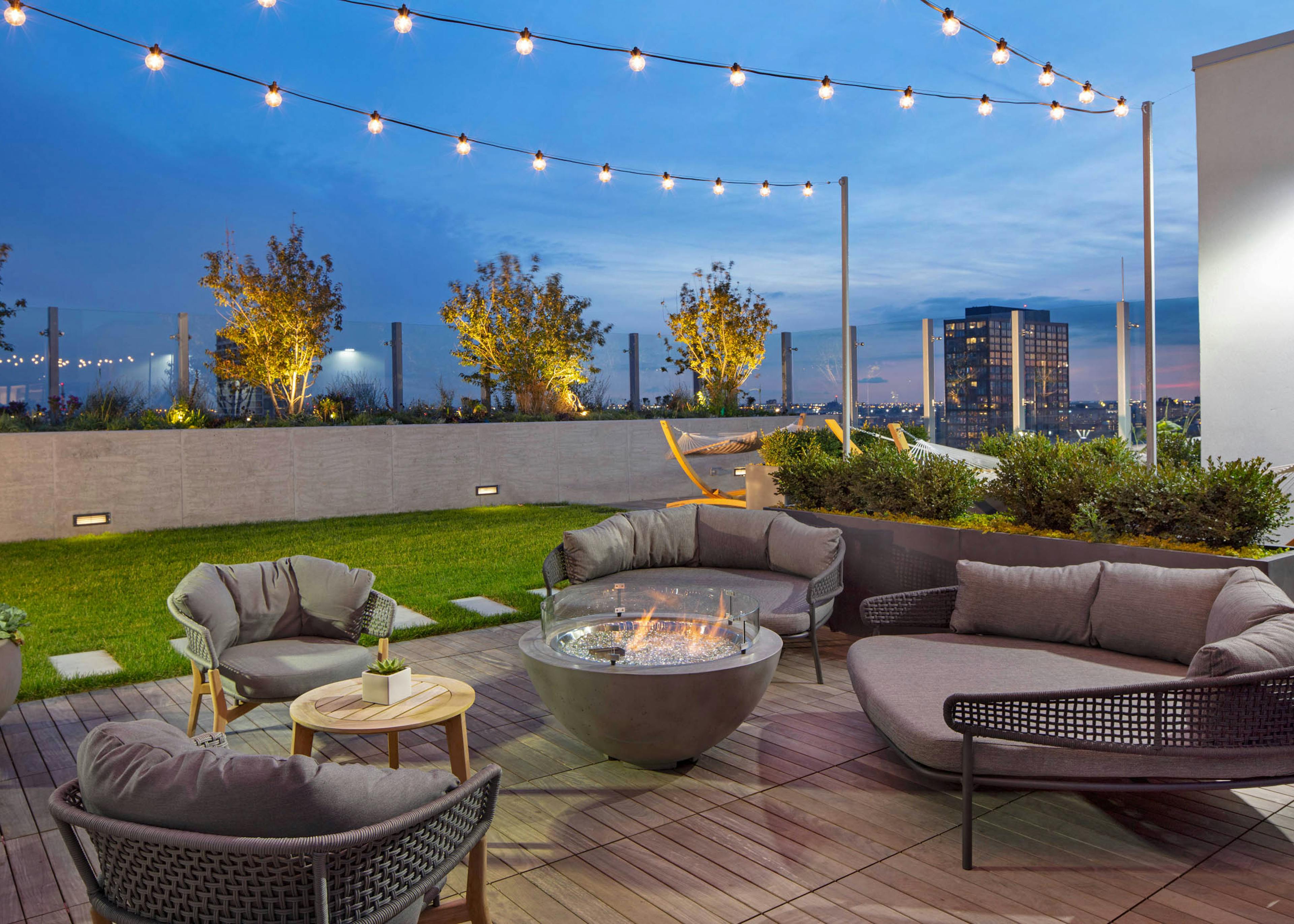 Nighttime view of rooftop firepits with grey lounge seating and string lights at AMLI West Loop