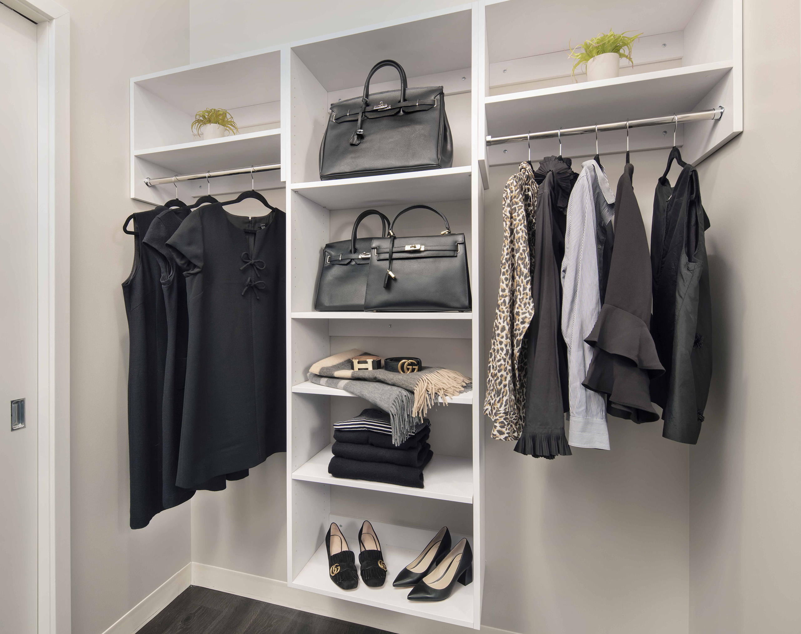 Spacious walk-in closet at AMLI West Loop with white built-in shelving and various clothing items hung up and on shelves.
