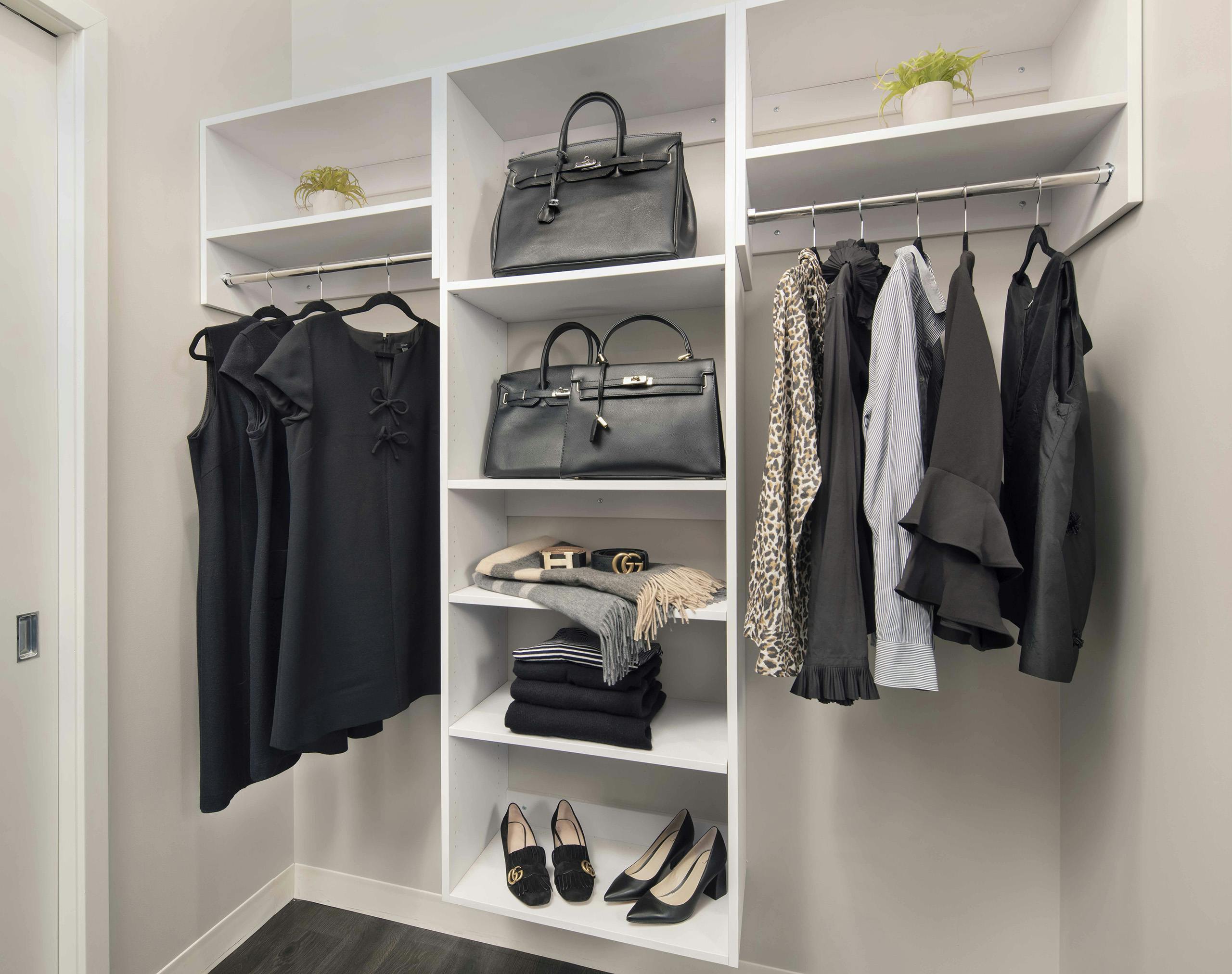 Spacious walk-in closet at AMLI West Loop with white built-in shelving and various clothing items hung up and on shelves.