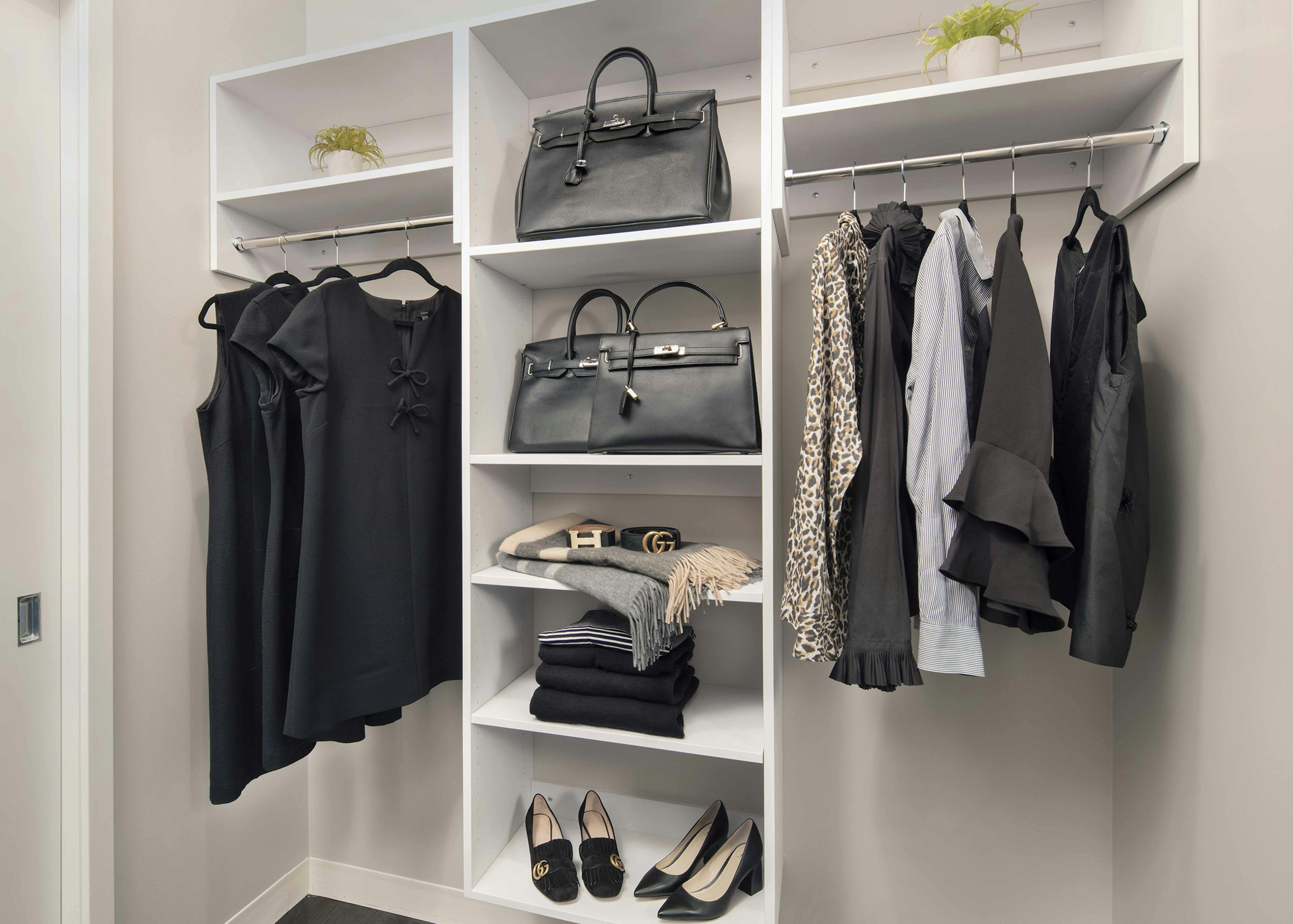 Spacious walk-in closet at AMLI West Loop with white built-in shelving and various clothing items hung up and on shelves.