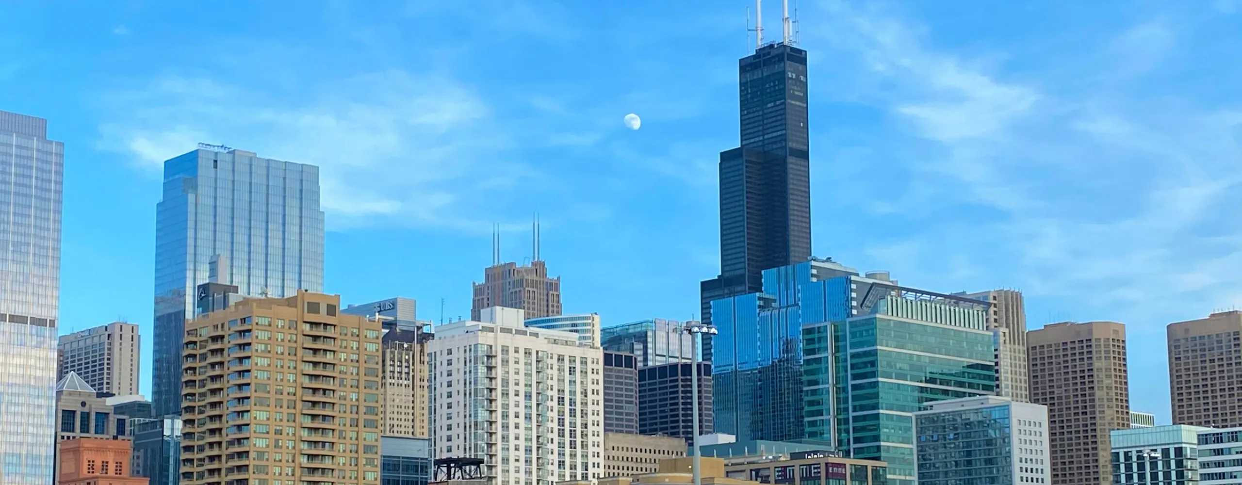 Daytime shot of the Chicago skyline with the Willis Tower and a colorful mural on a building in the foreground.