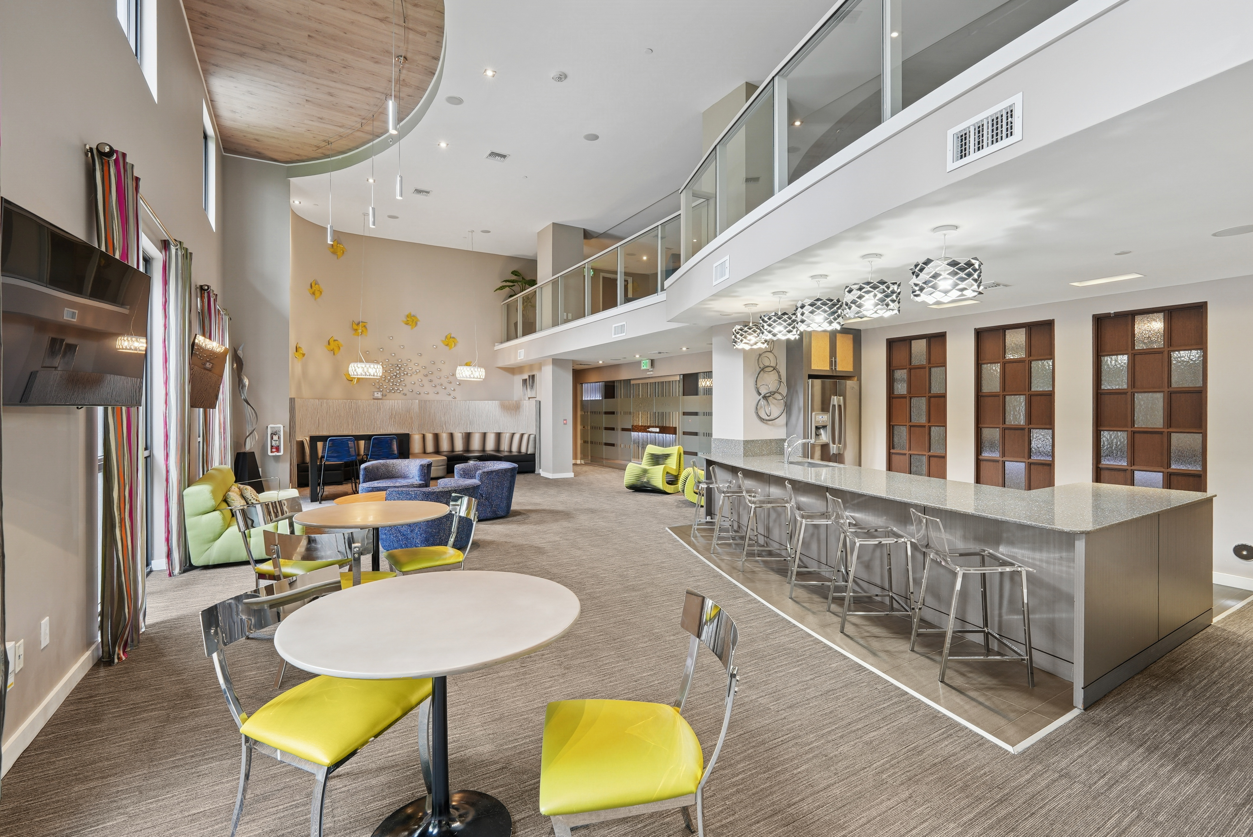 Resident clubroom at AMLI Dadeland apartments featuring a long quartz bar top with stools and couches and smaller tables