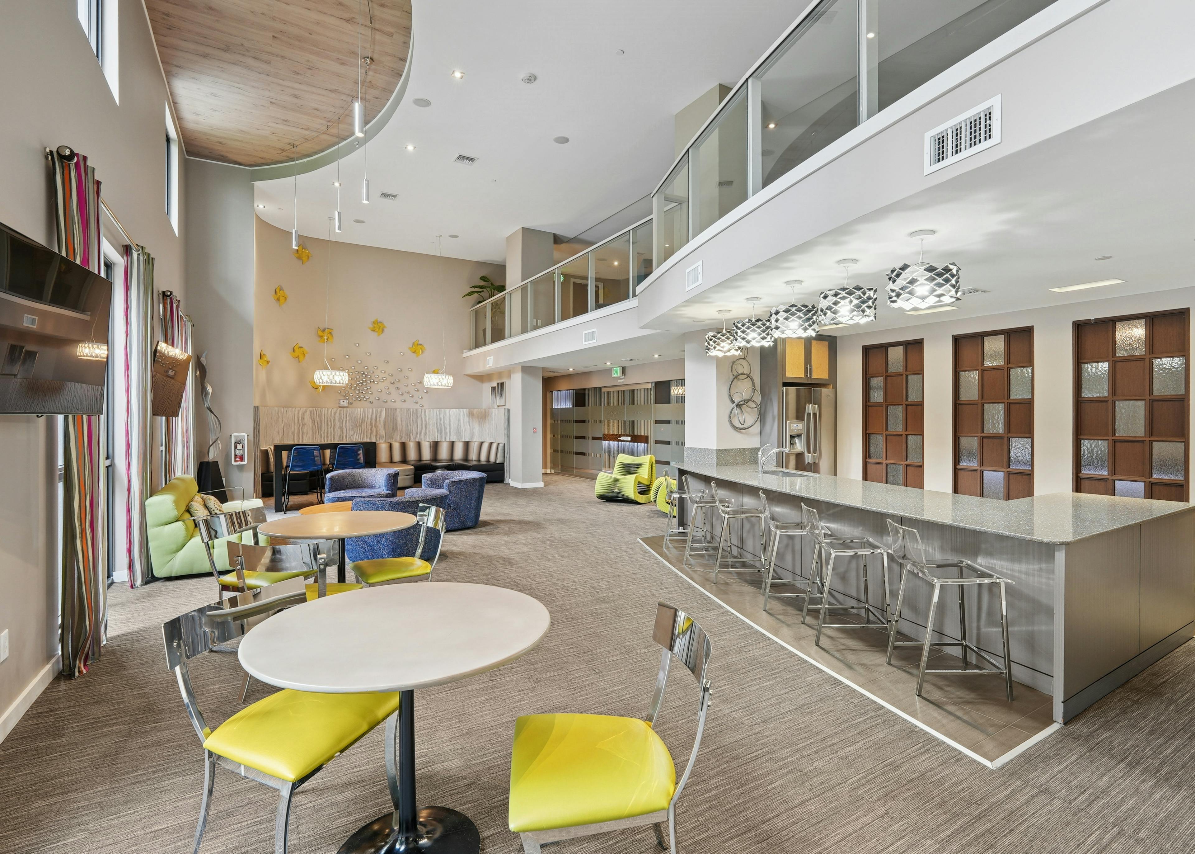 Resident clubroom at AMLI Dadeland apartments featuring a long quartz bar top with stools and couches and smaller tables