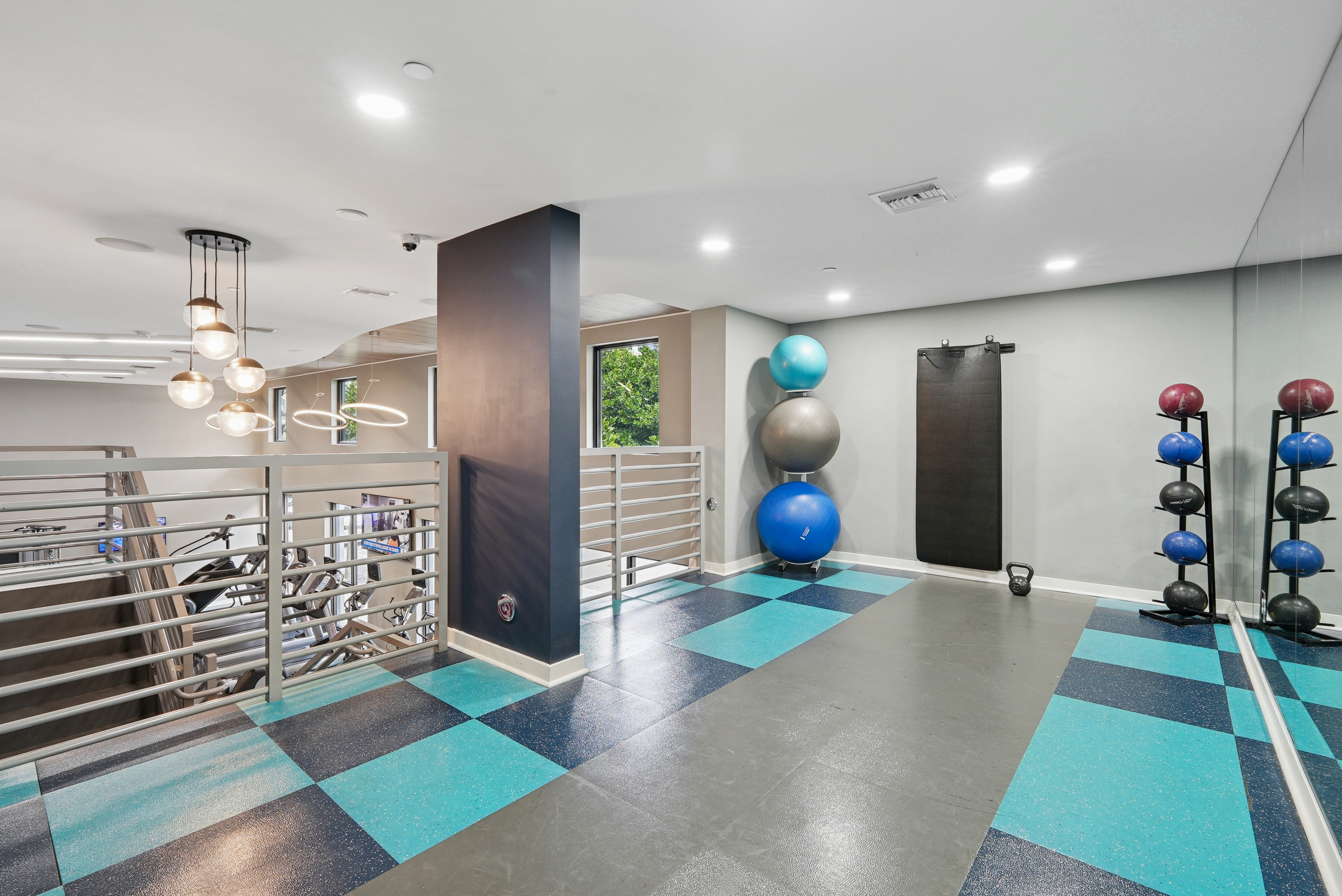 Fitness center at AMLI Dadeland apartments with medicine balls and kettle bells and yoga mats hung up on the wall and mirrors