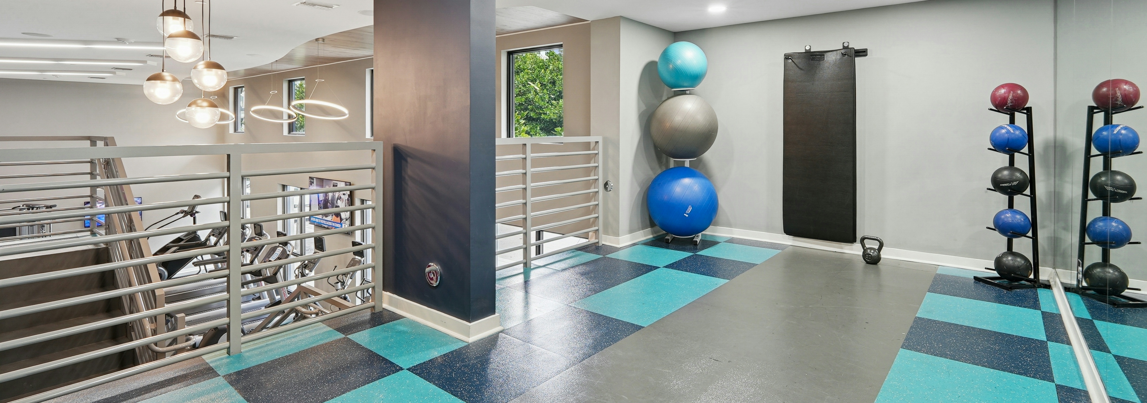 Fitness center at AMLI Dadeland apartments with medicine balls and kettle bells and yoga mats hung up on the wall and mirrors