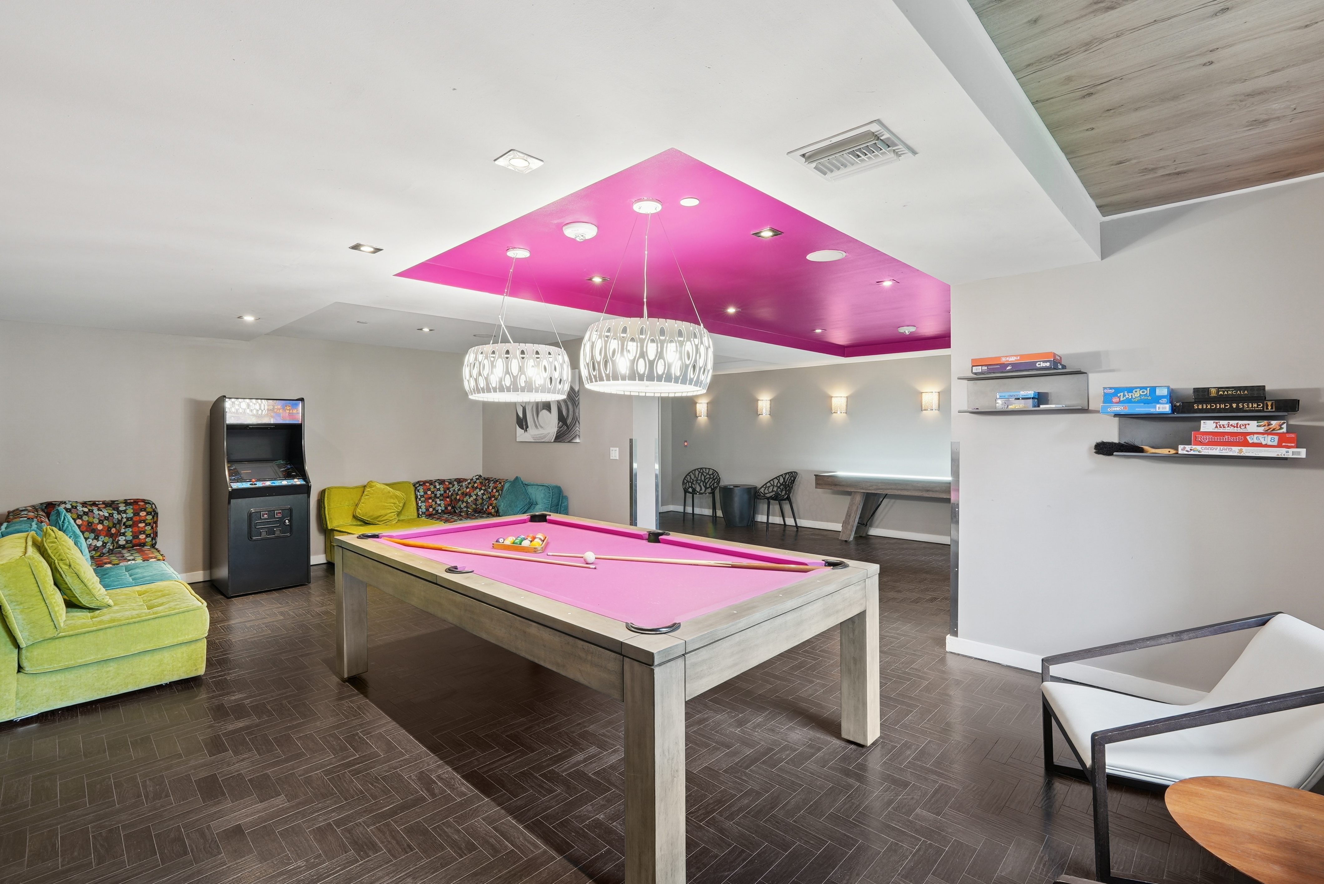 Resident clubroom at AMLI Dadeland apartments showcasing a pool table and an arcade machine and board games and couches