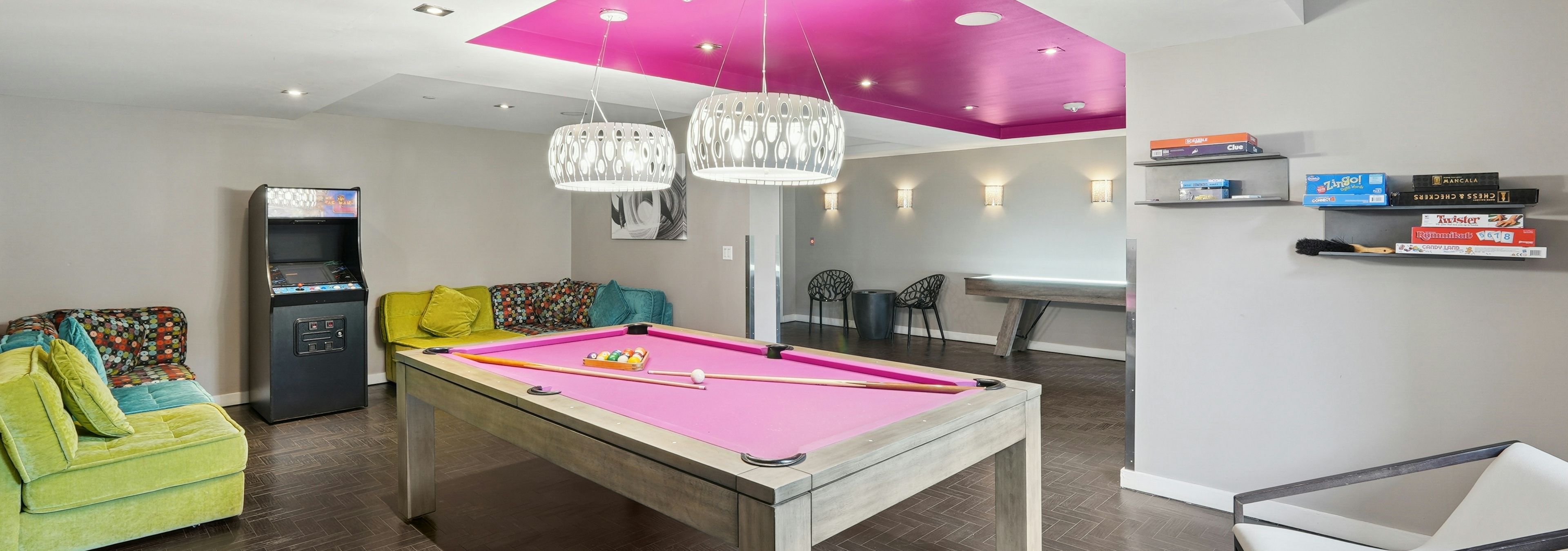 Resident clubroom at AMLI Dadeland apartments showcasing a pool table and an arcade machine and board games and couches