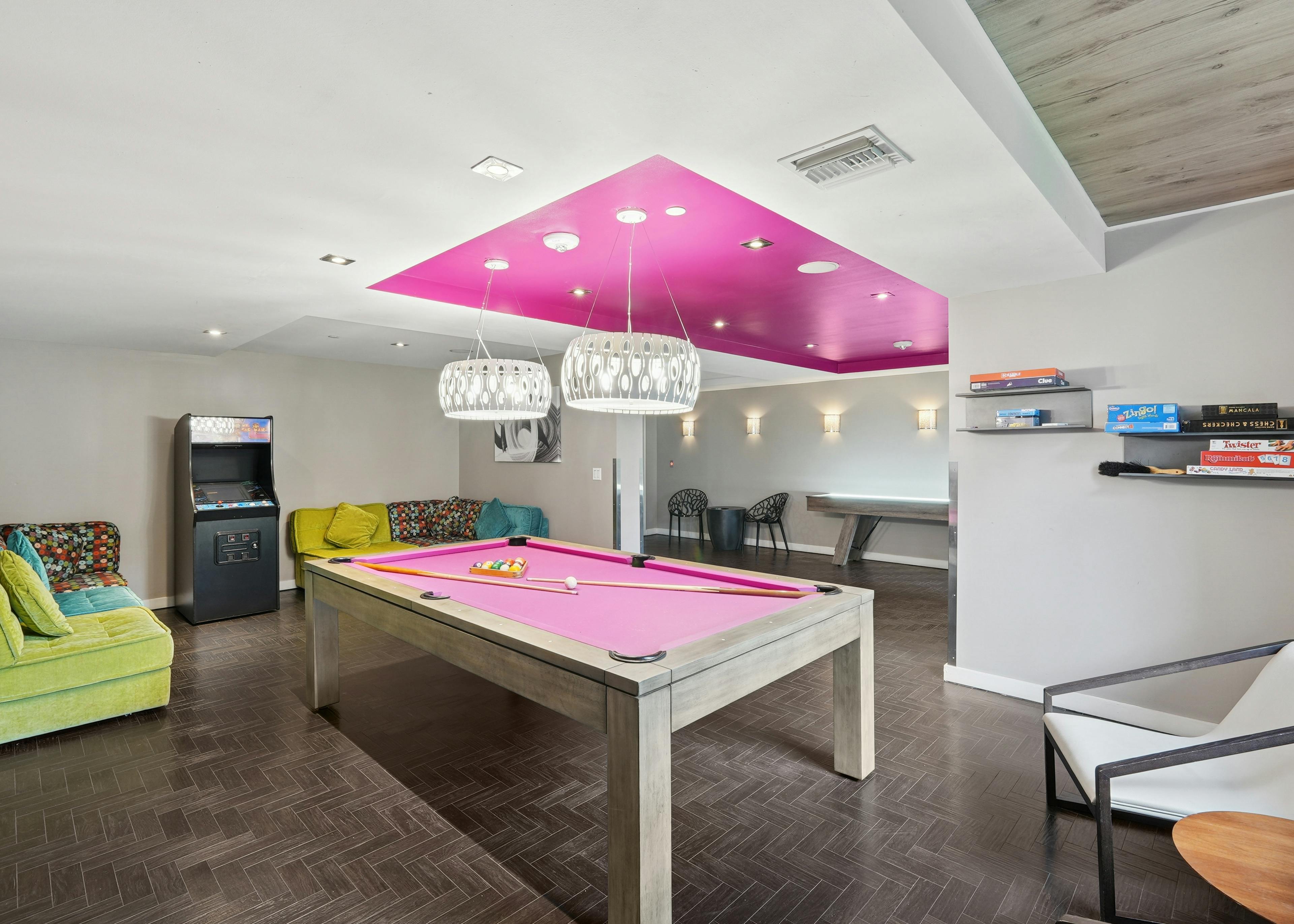 Resident clubroom at AMLI Dadeland apartments showcasing a pool table and an arcade machine and board games and couches