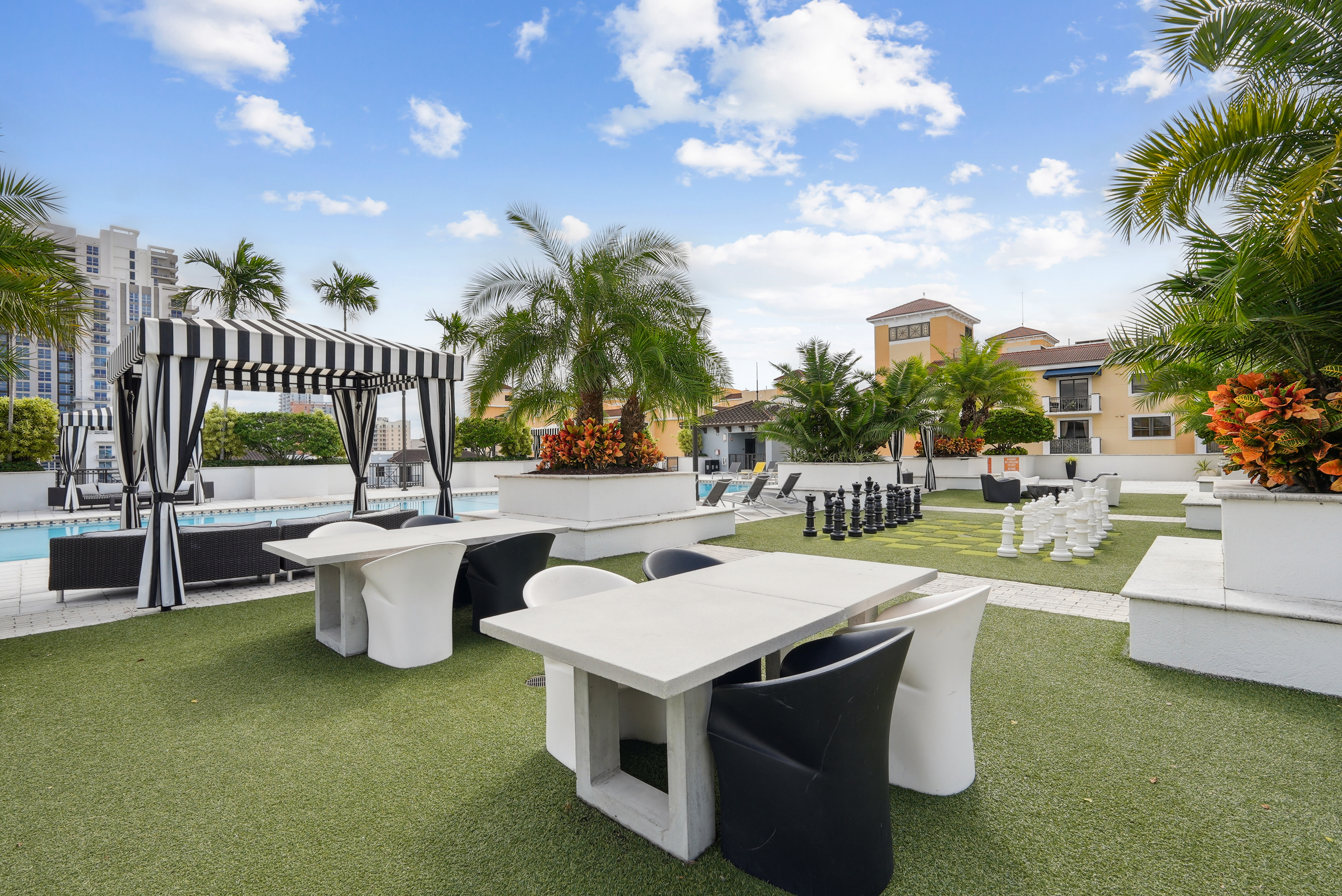 Exterior view of the rooftop amenity space at AMLI Dadeland with a swimming pool and several seating areas and palm trees