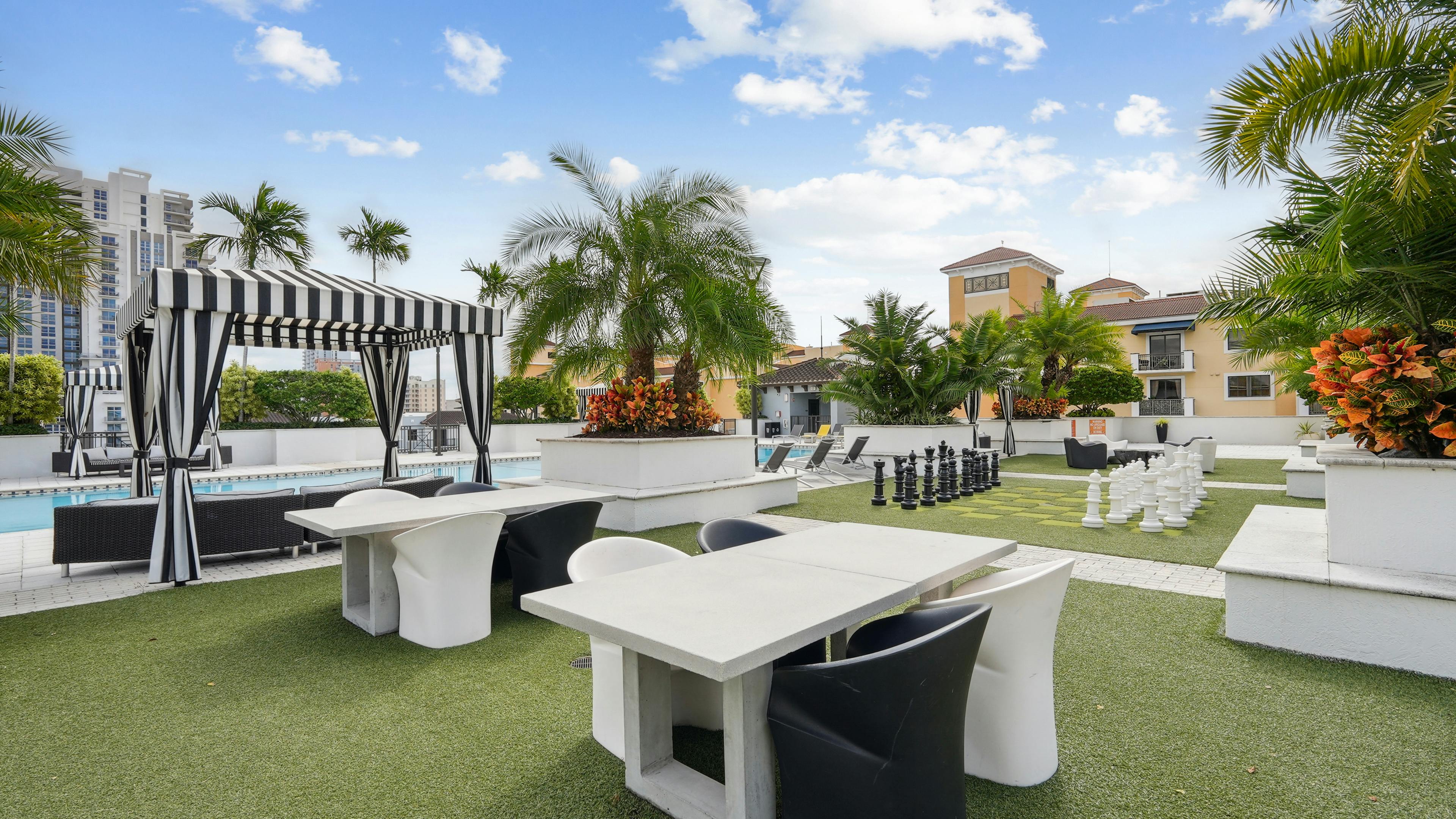 Exterior view of the rooftop amenity space at AMLI Dadeland with a swimming pool and several seating areas and palm trees