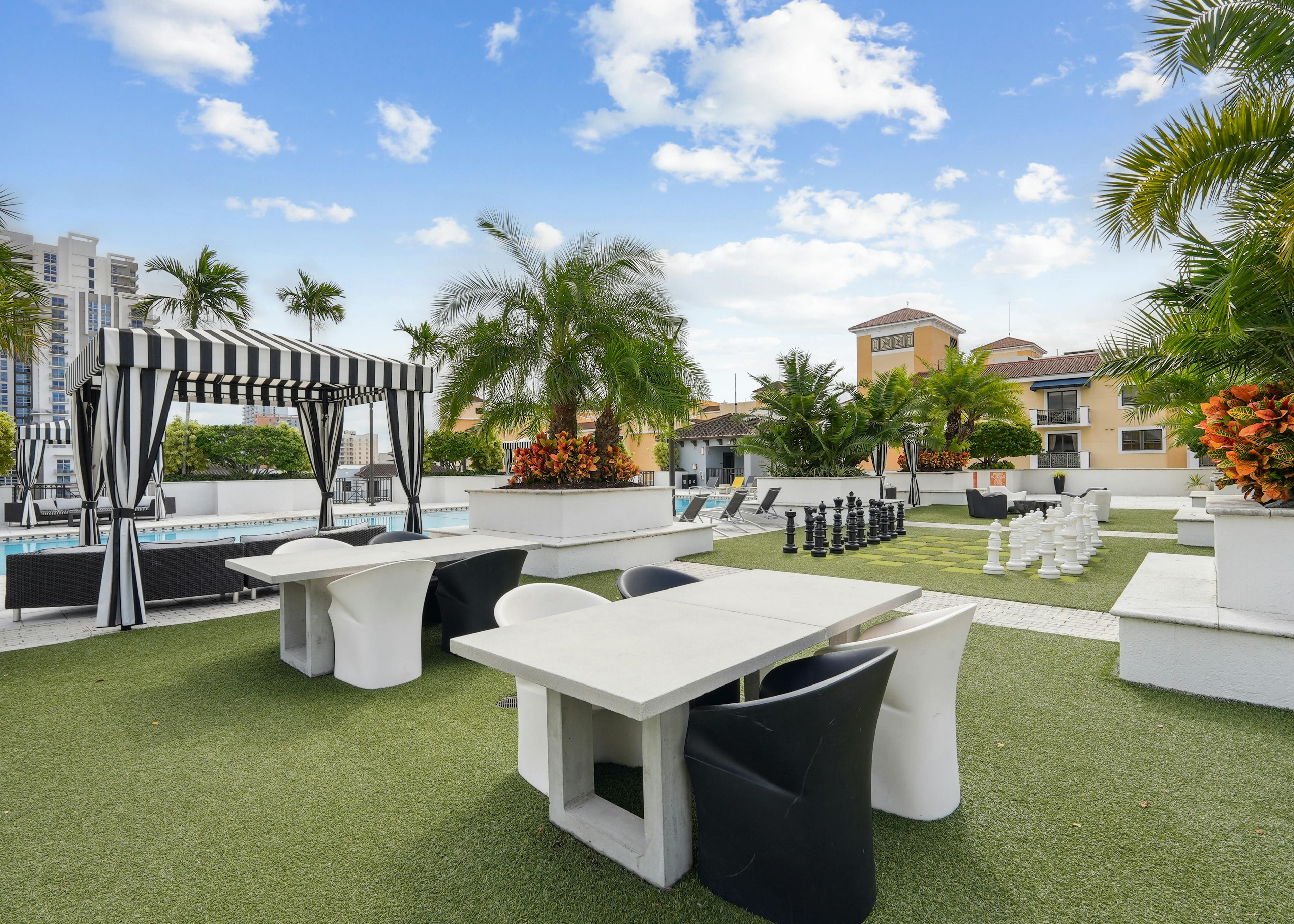 Exterior view of the rooftop amenity space at AMLI Dadeland with a swimming pool and several seating areas and palm trees