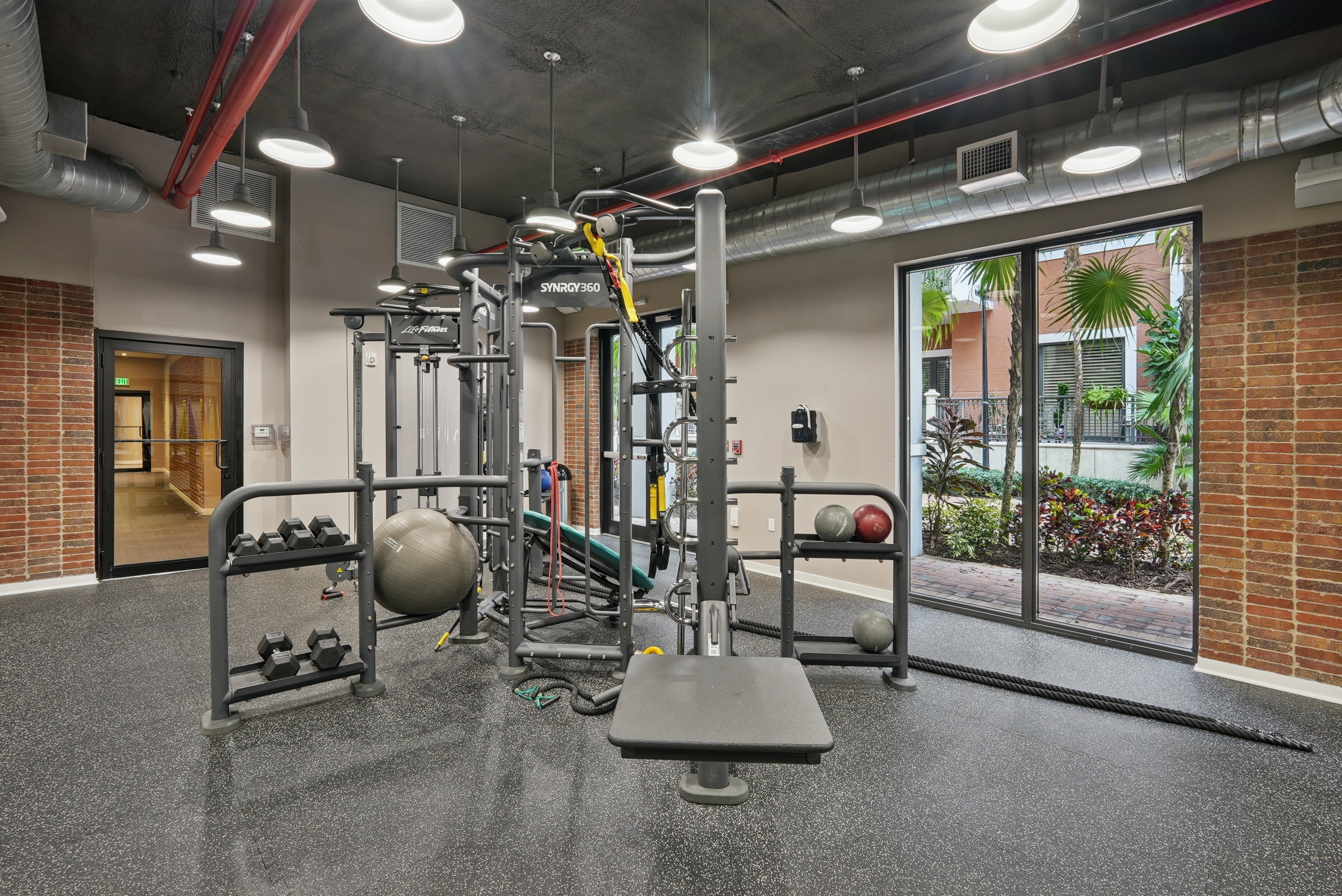 Interior view of a fitness center studio at AMLI Dadeland apartments with medicine balls and dumbbell weights and ropes