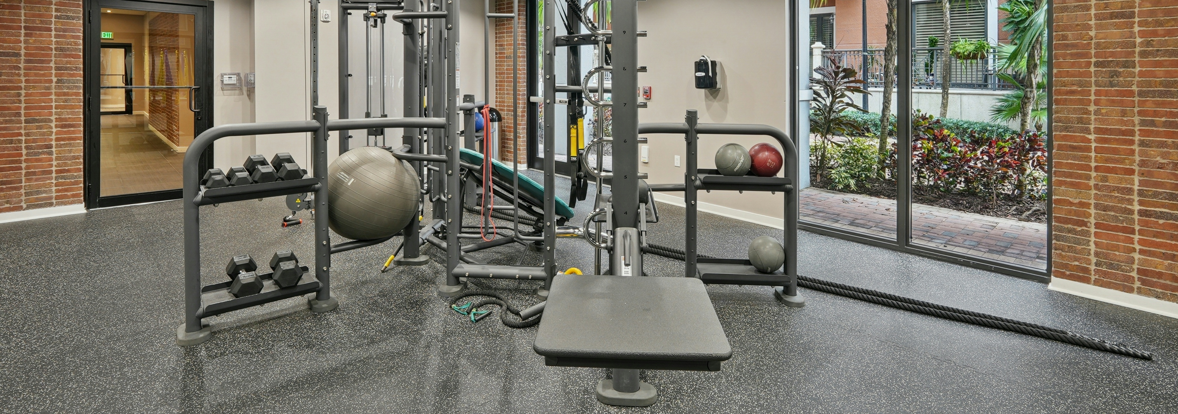 Interior view of a fitness center studio at AMLI Dadeland apartments with medicine balls and dumbbell weights and ropes