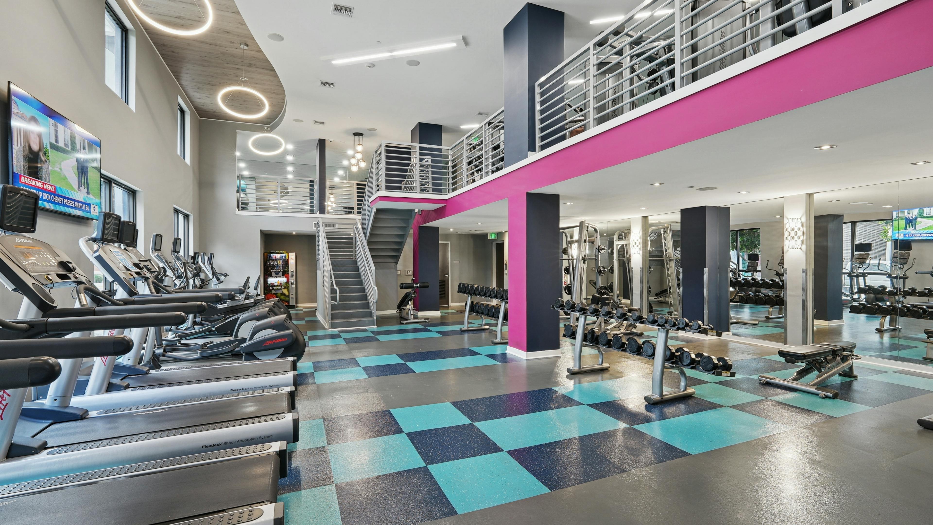 AMLI Dadeland apartments fitness center with a teal and pink color scheme and vaulted ceilings and various workout equipment