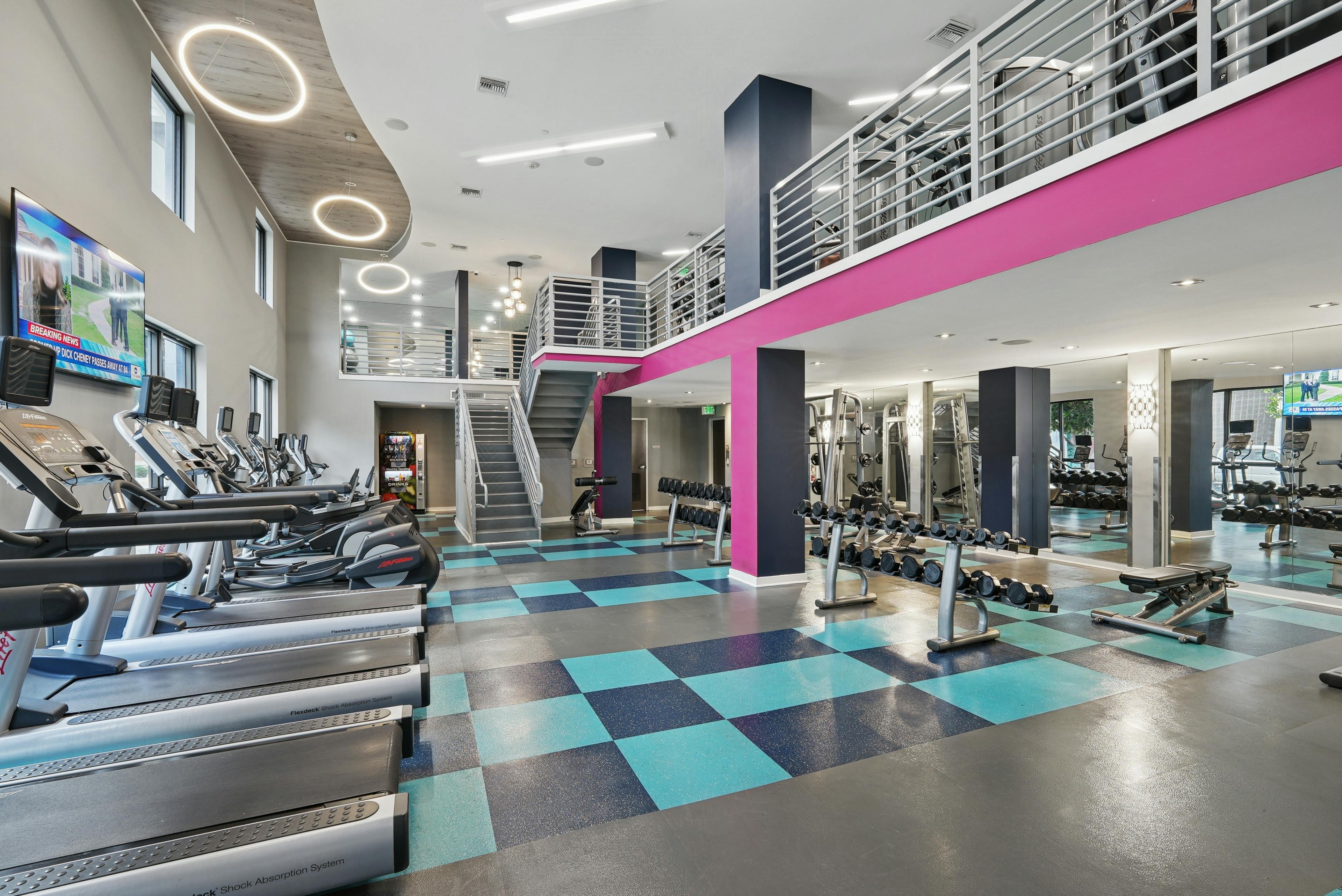AMLI Dadeland apartments fitness center with a teal and pink color scheme and vaulted ceilings and various workout equipment