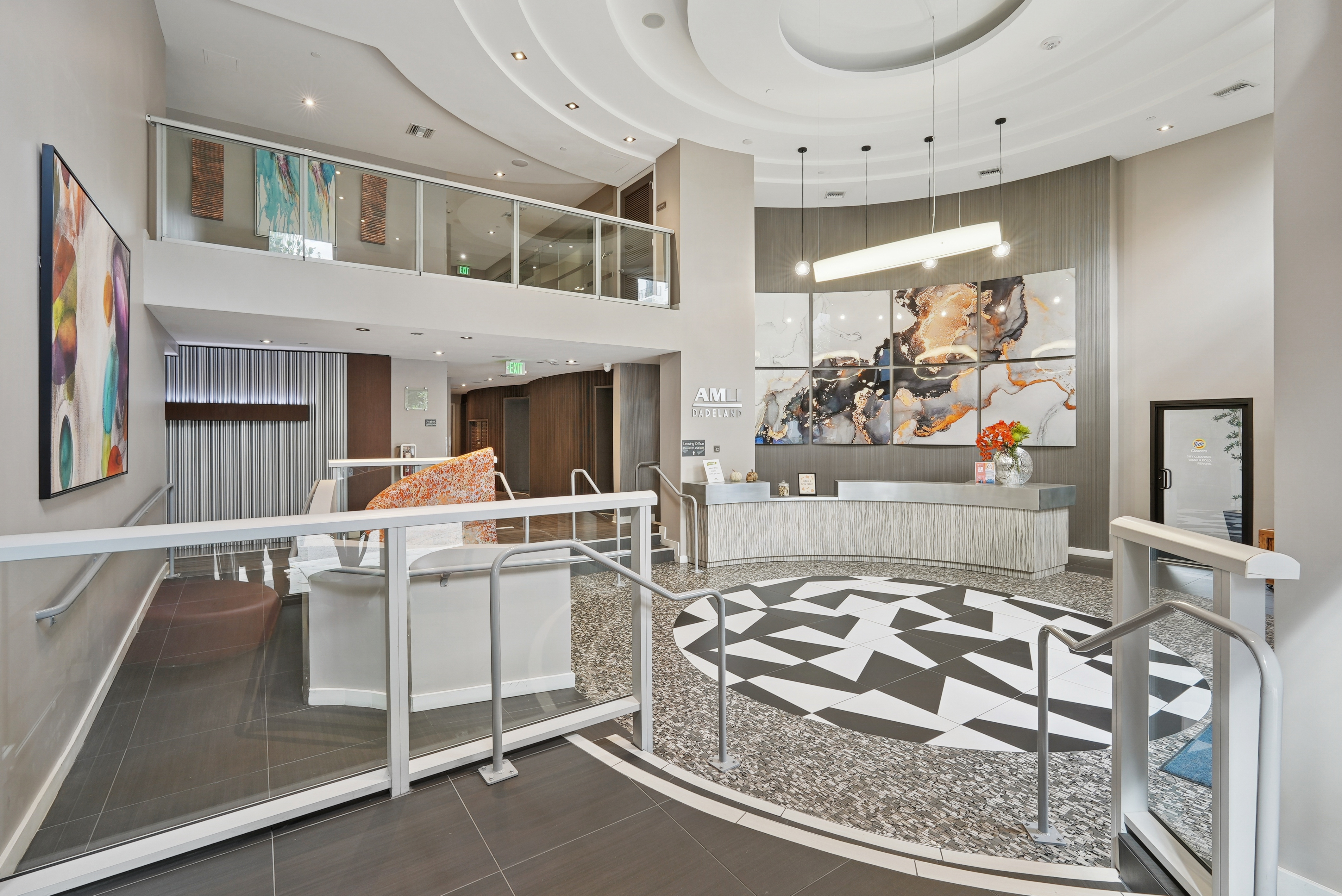 Interior view of the leasing office at AMLI Dadeland apartments with a curved front desk with flowers and vibrant wall art